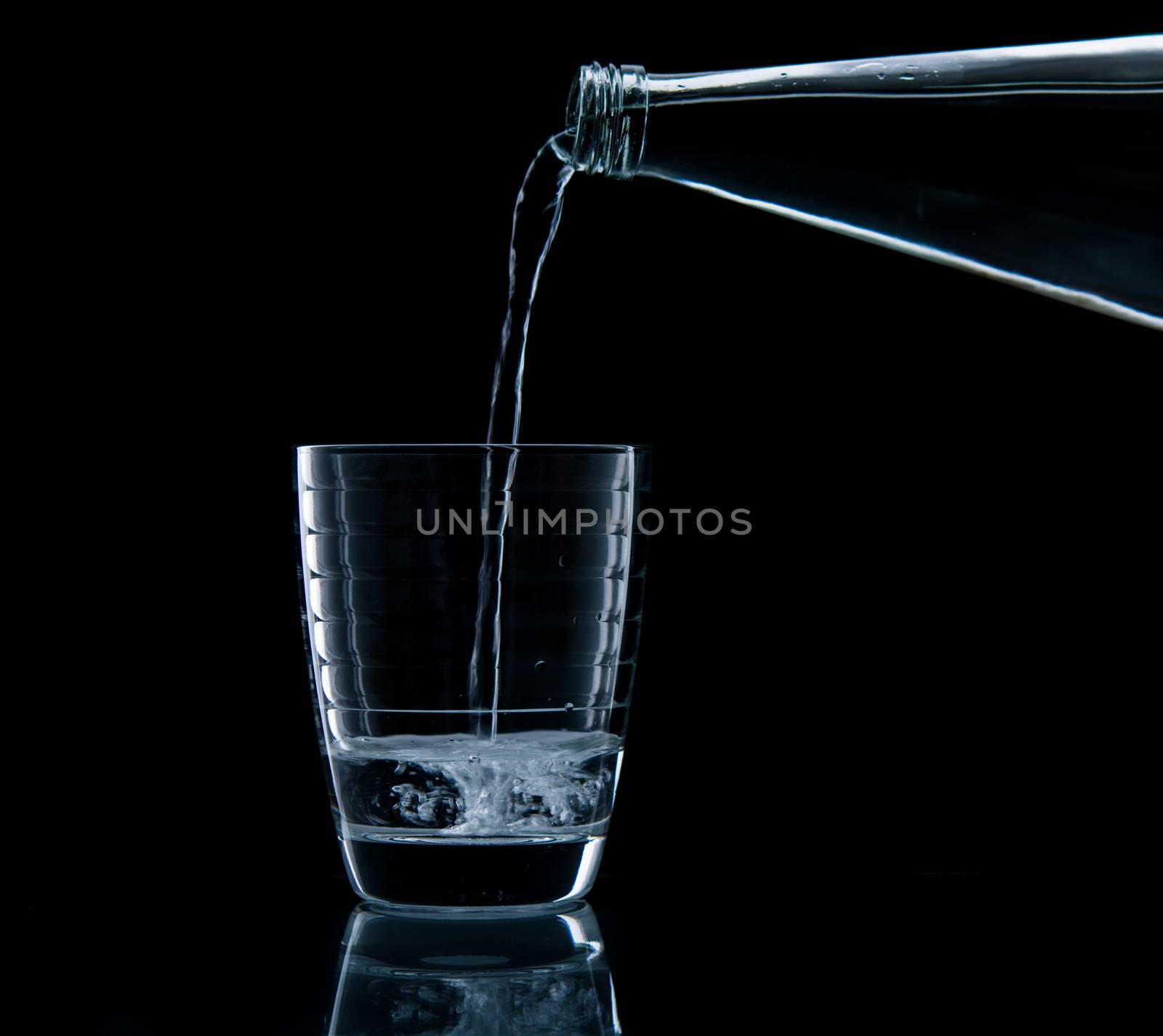 Pouring water on glass on over black background