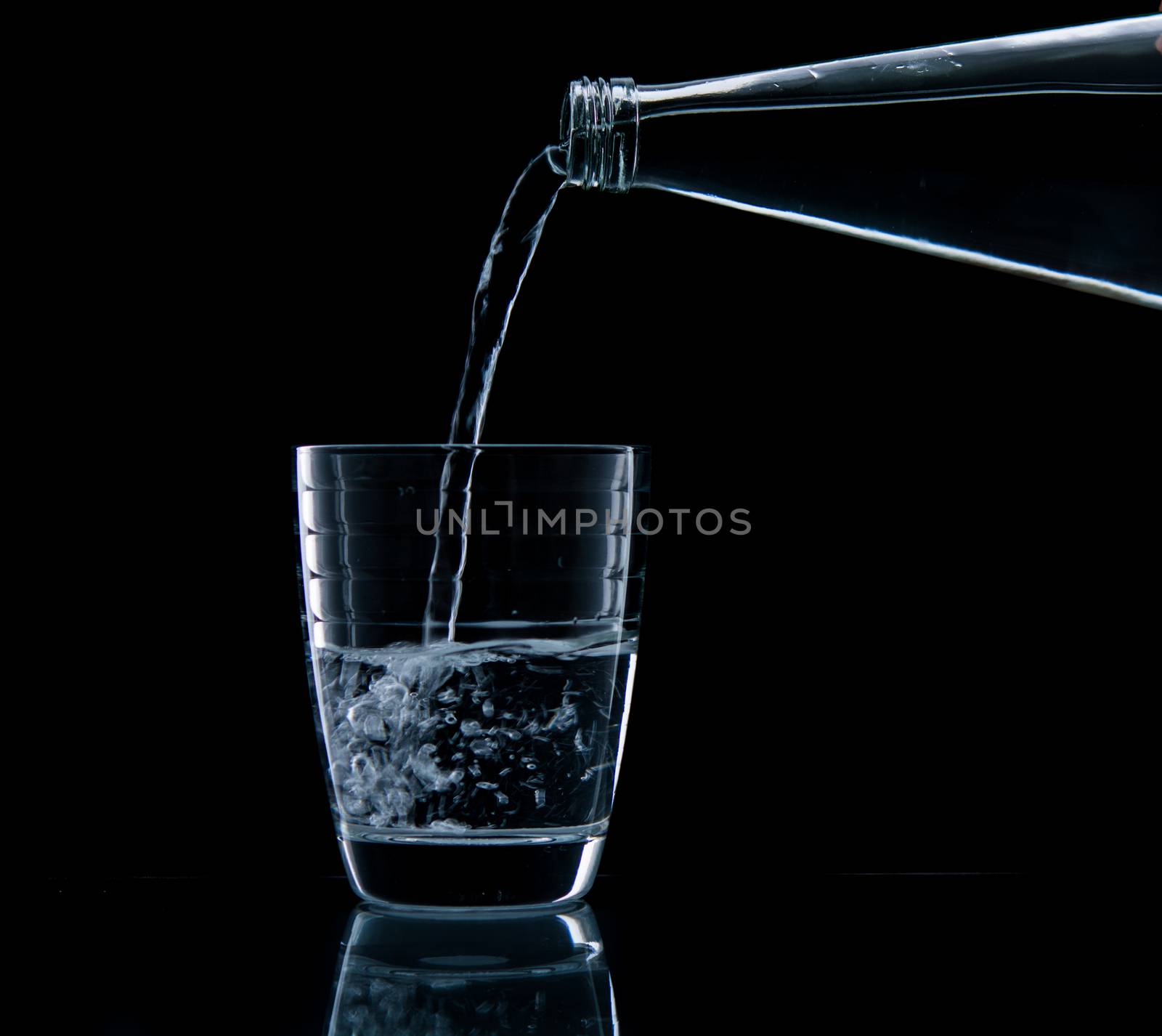 Pouring water on glass on over black background
