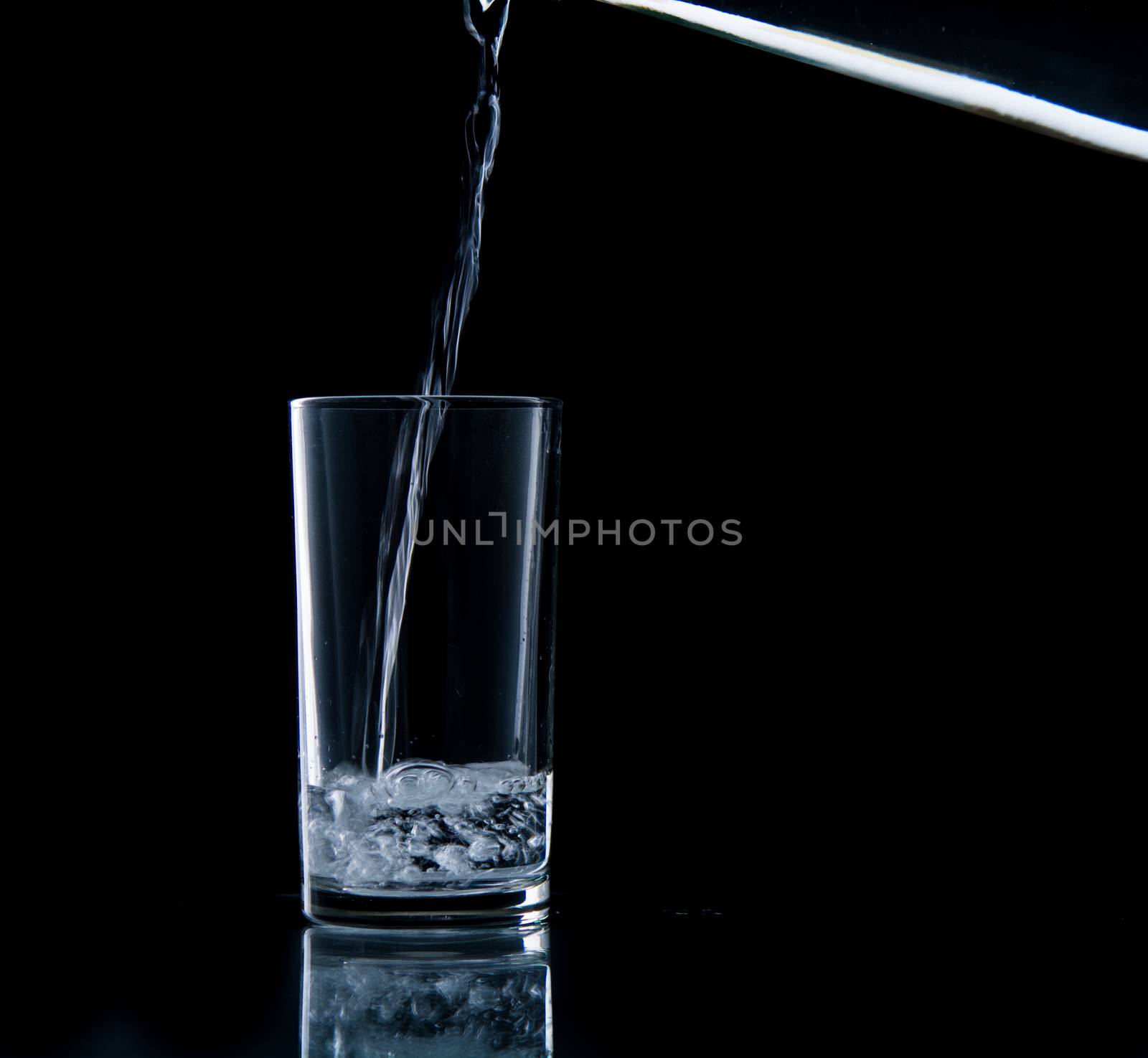 Pouring water on glass on over black background