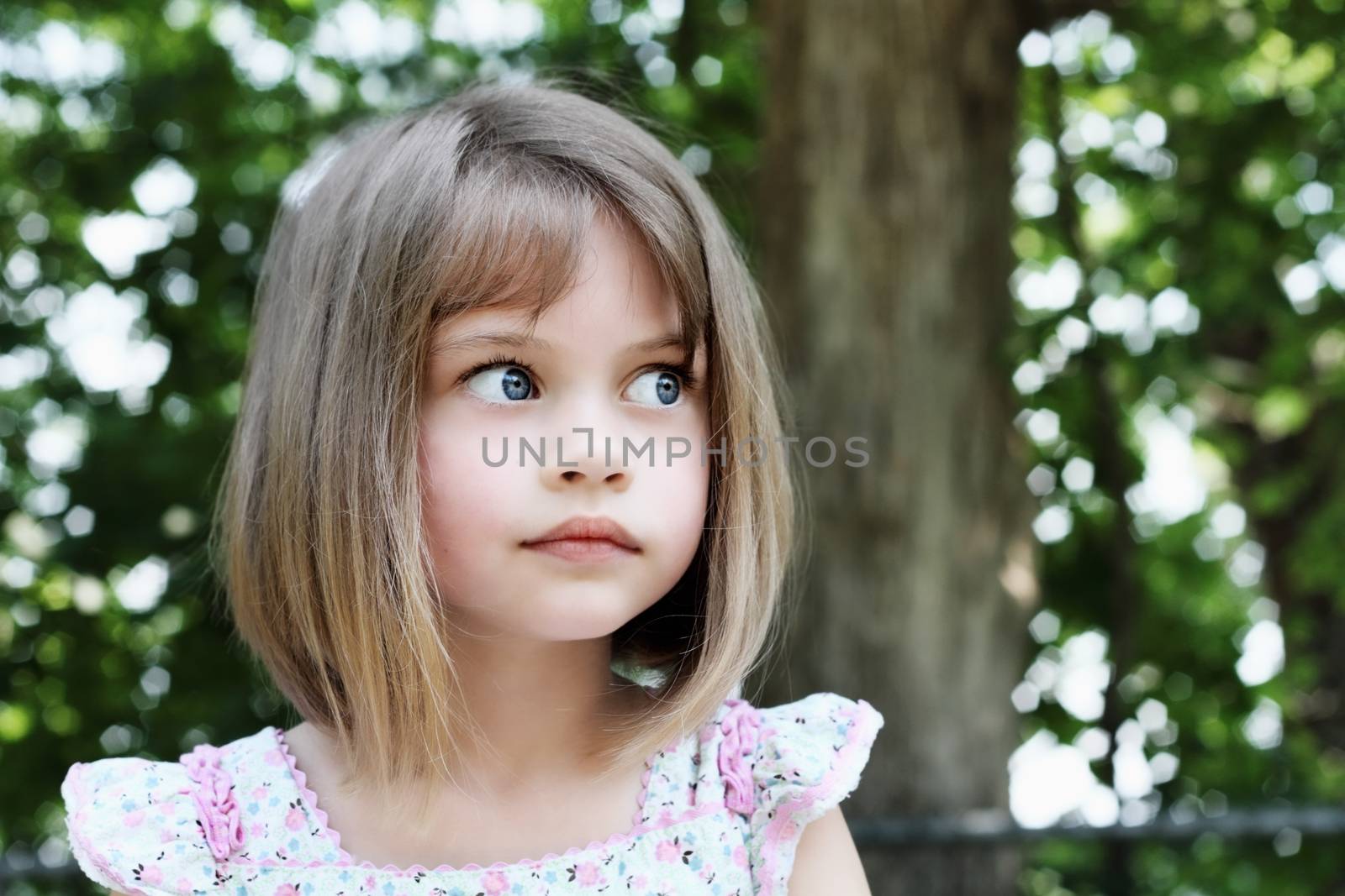 Cute little girl with bobbed hair cut looking away from camera. Extreme shallow depth of field.