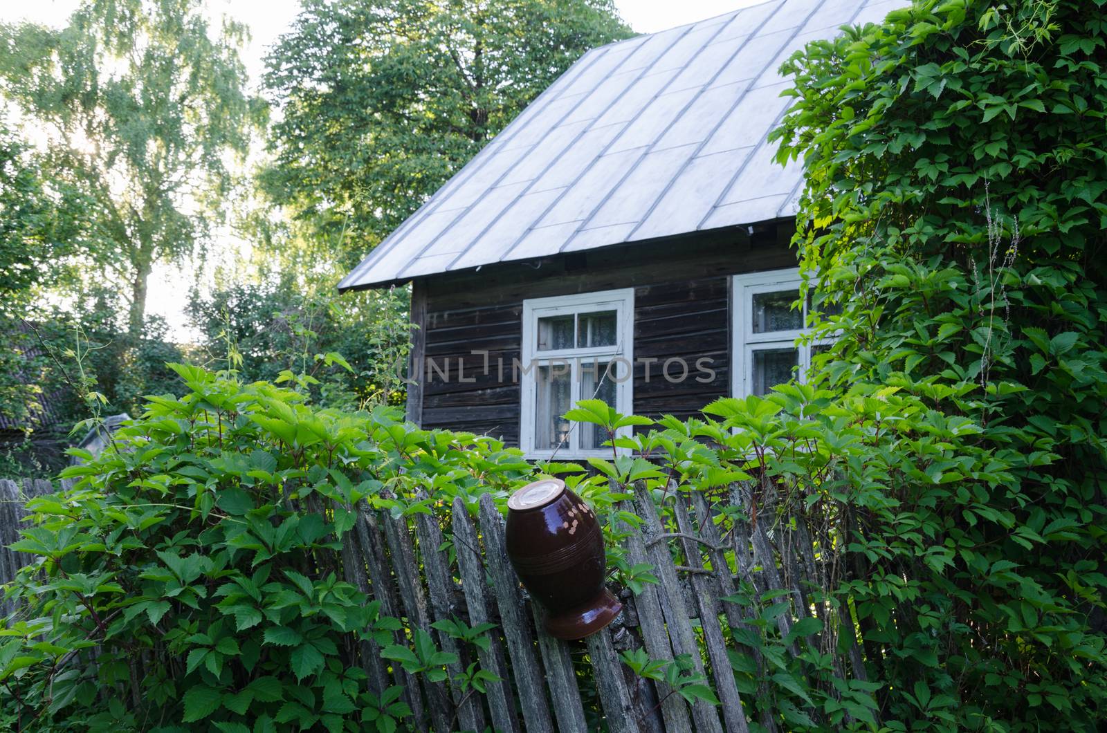 old country style house with windows and wooden fence with clay jug
