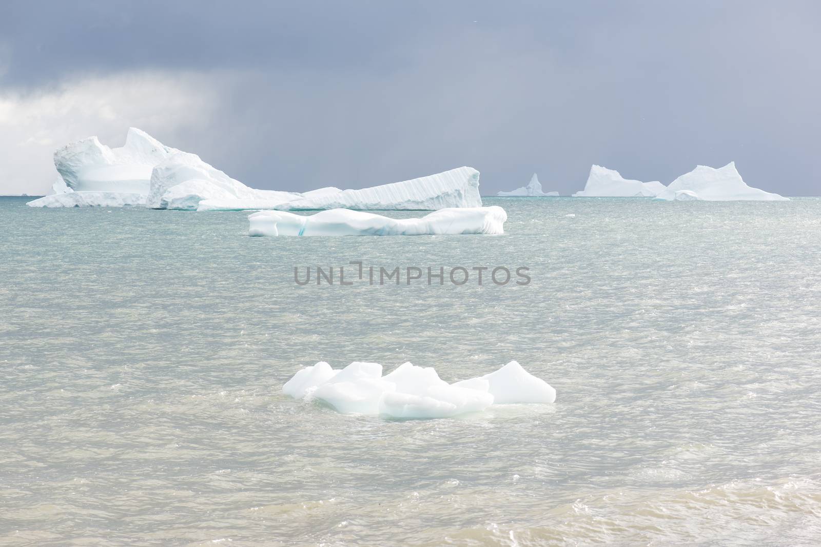 Beautiful icebergs in the sun and in front of a dark sky