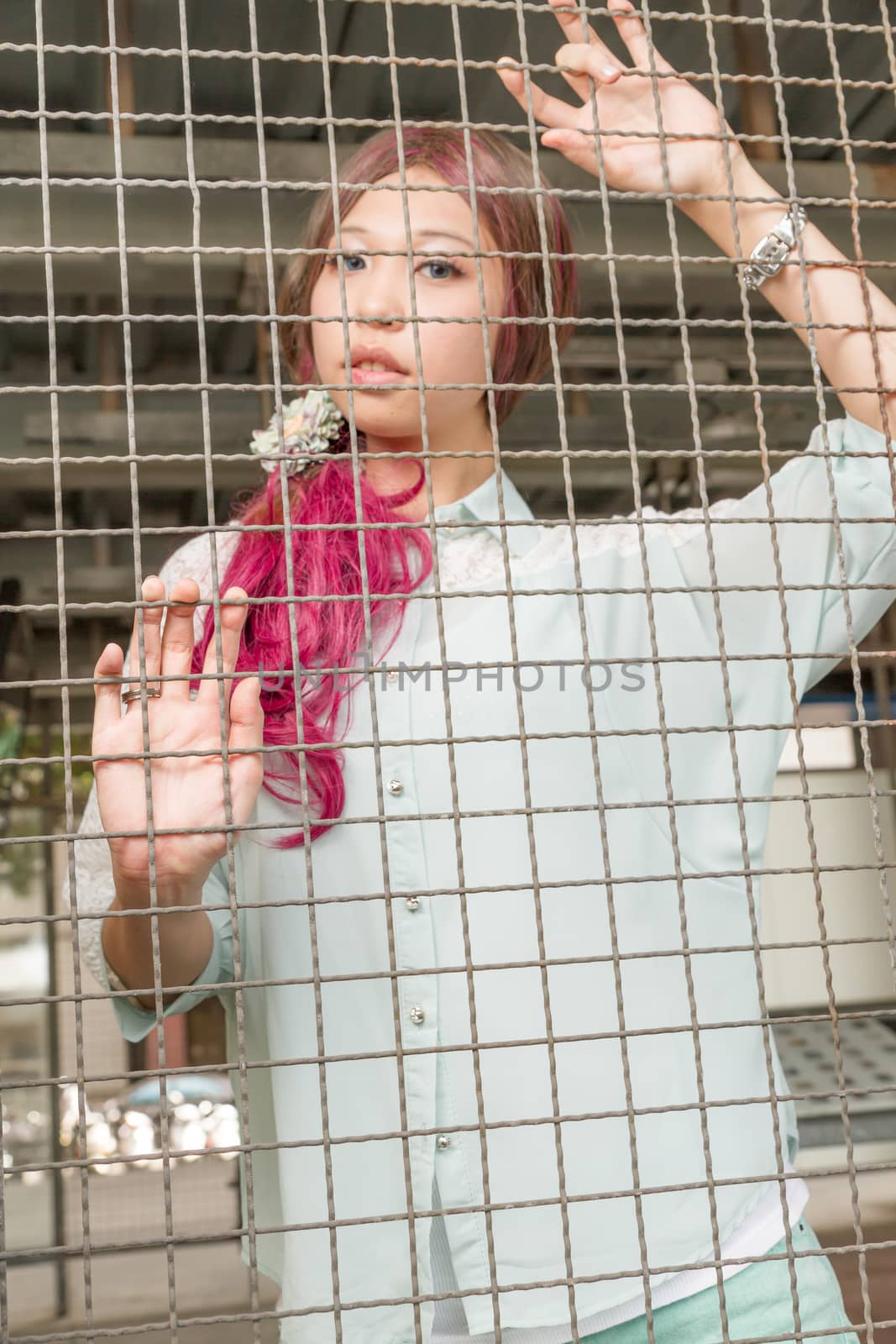 Asian woman behind a metal fence by imagesbykenny