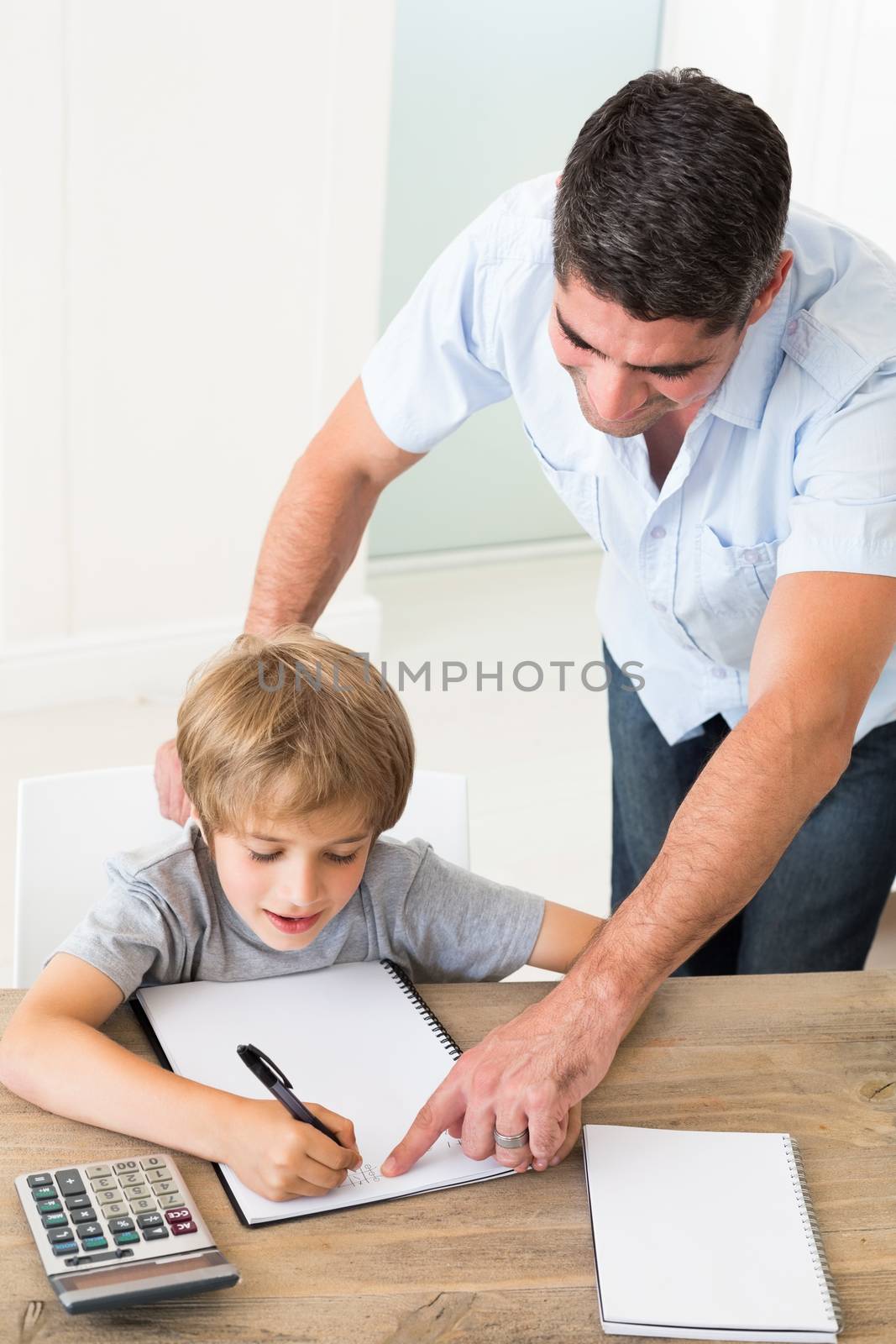 Father assisting boy in solving maths at home