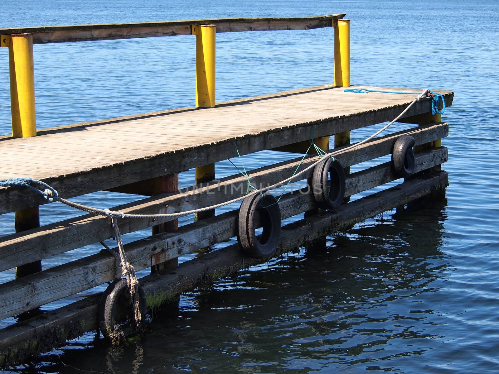 Small rural wooden bridge dock pier over crystal clear water