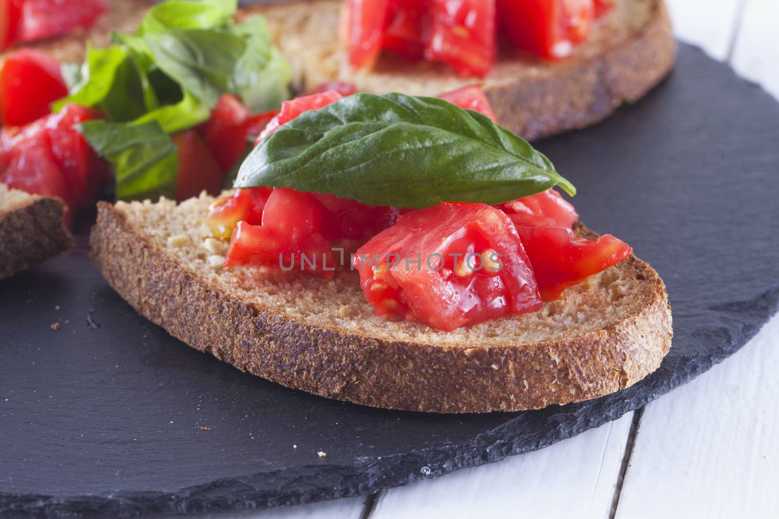 Bruschetta with tomato and basil over black stone