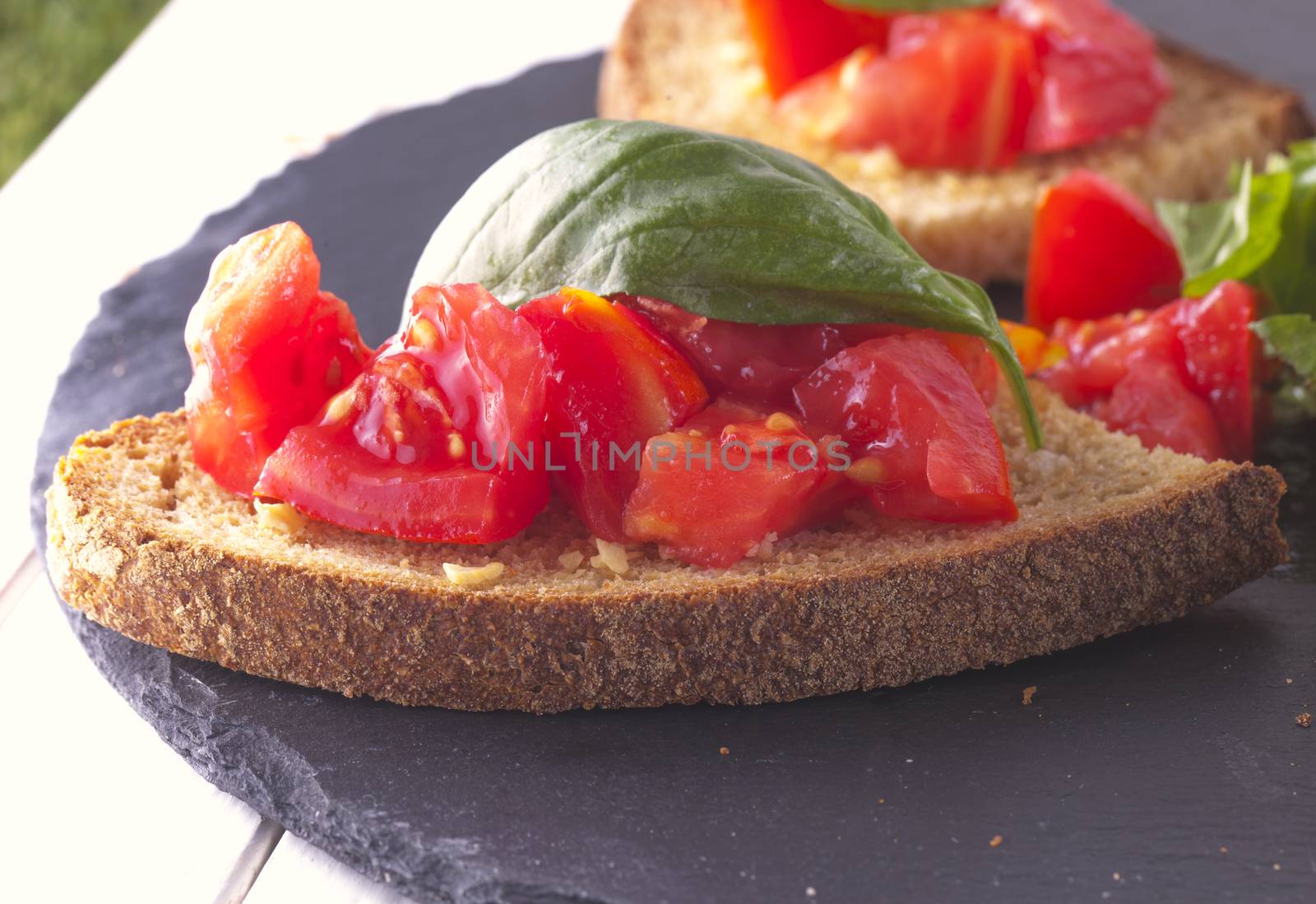 Bruschetta with tomato and basil over black stone