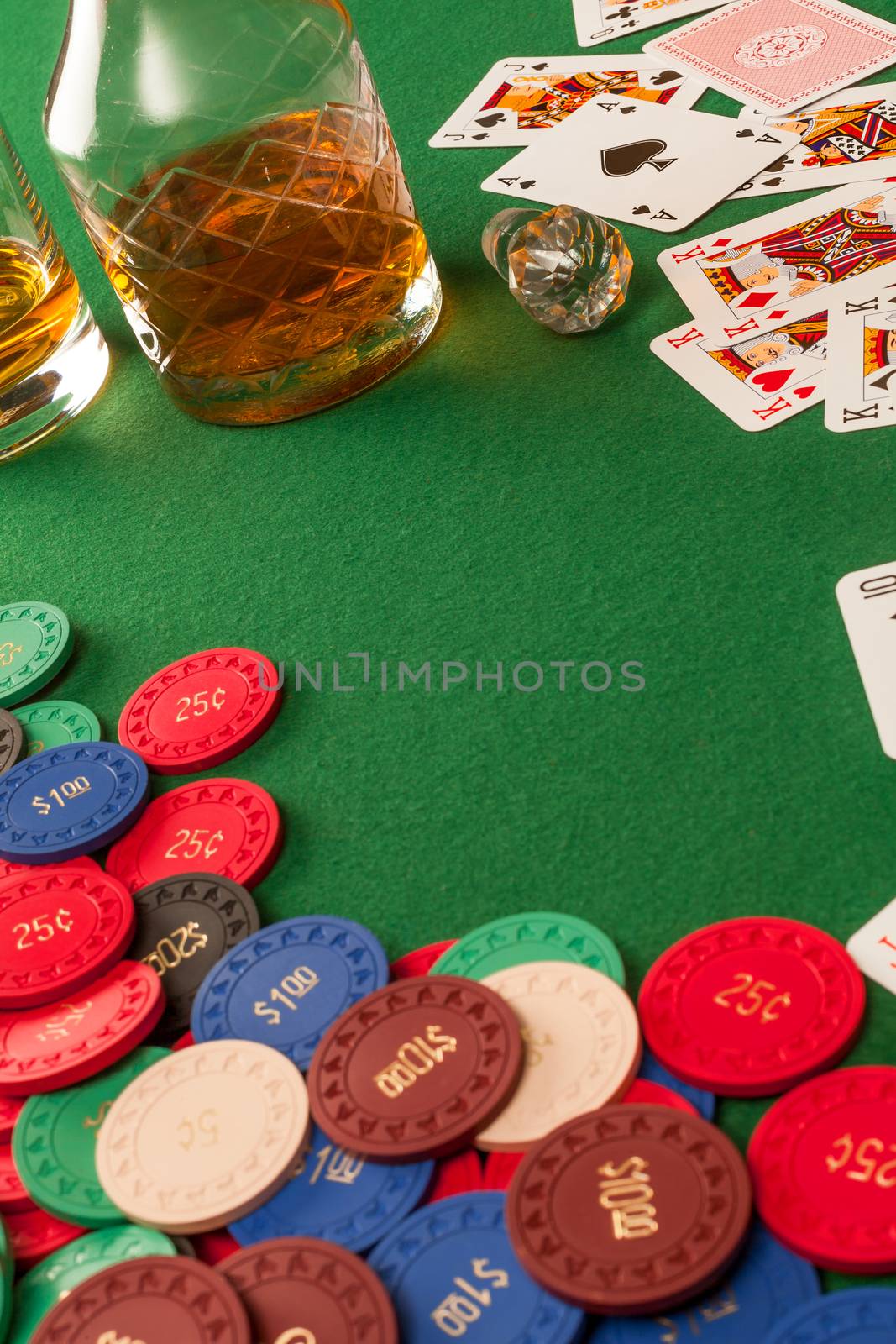 Photo of a poker table with gambling chips, cards and whisky.
