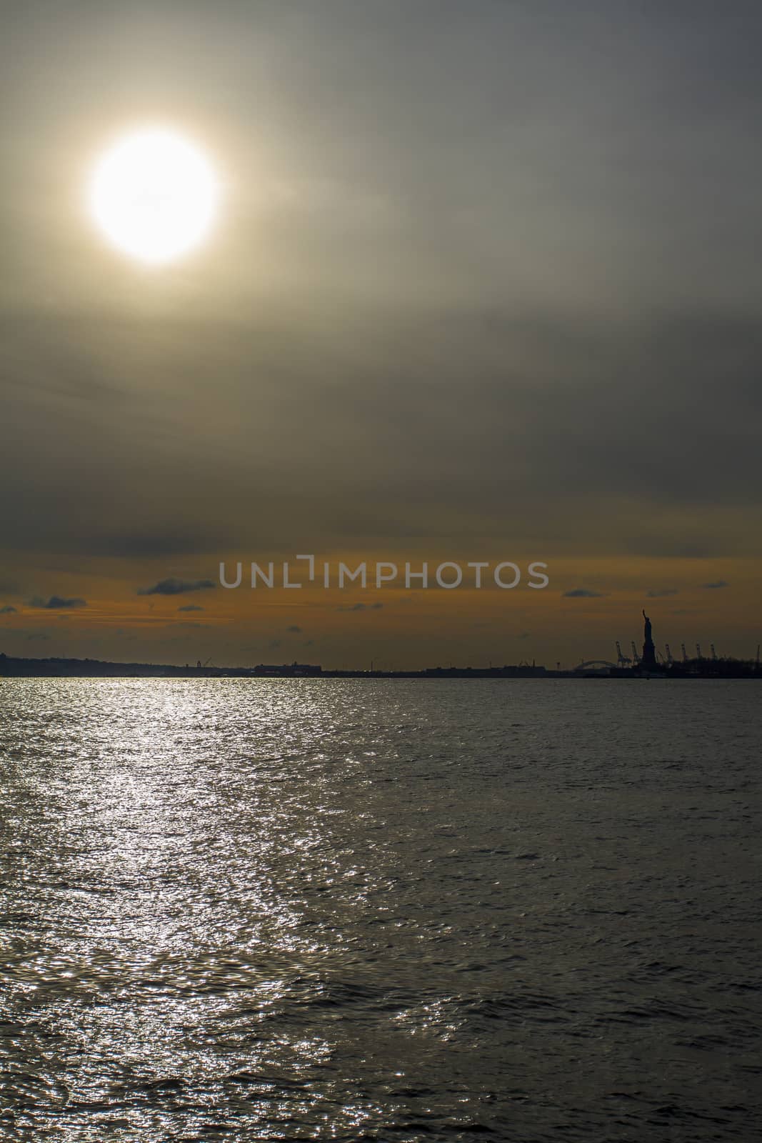 Sun setting over the hudson river with the statue of liberty in the background