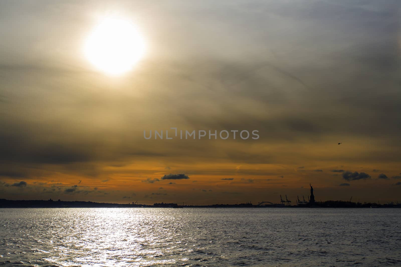 Sun setting over the hudson river with the statue of liberty in the background