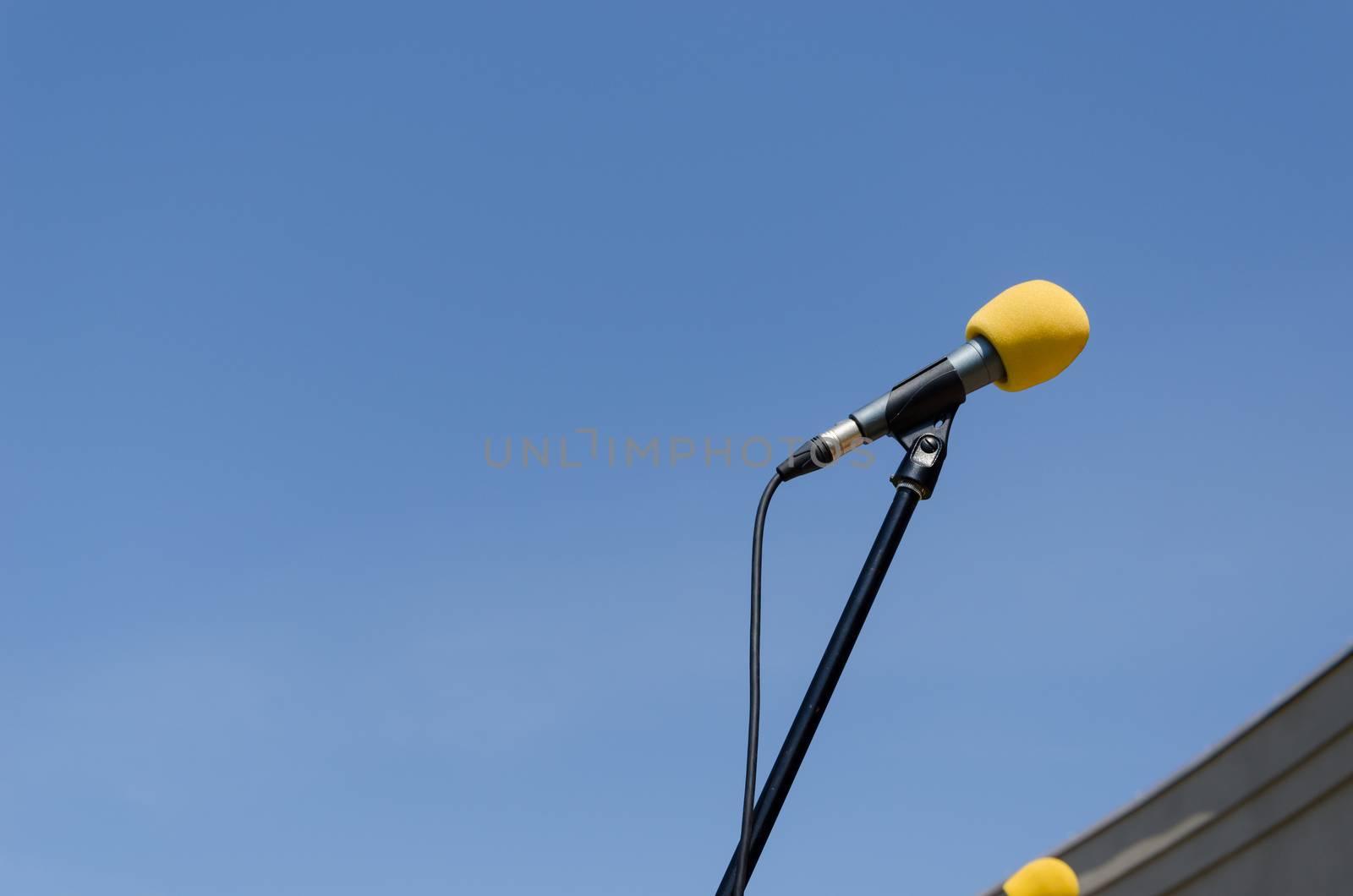 yellow microphone with stand on blue sky background