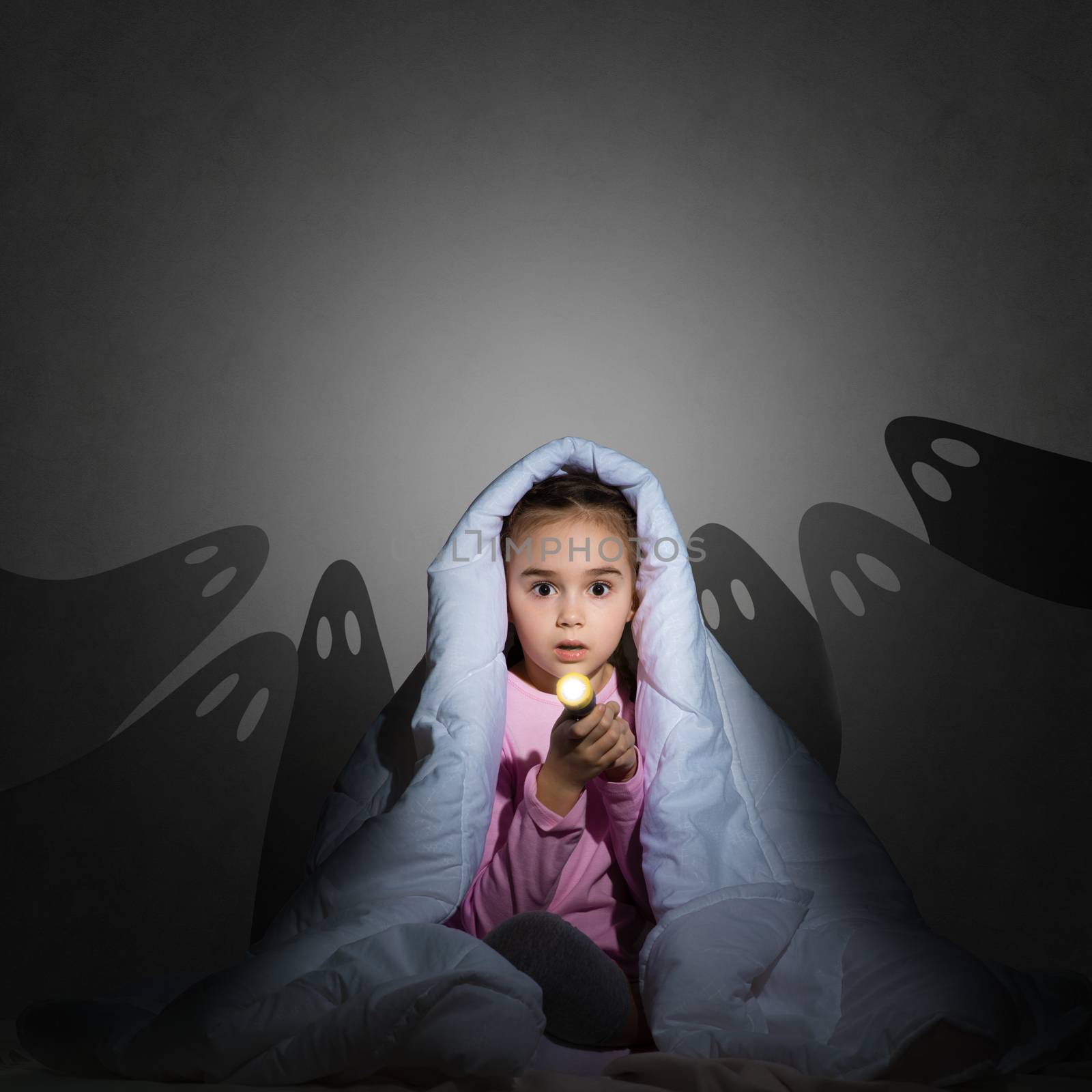 image of a girl under the covers with a flashlight the night afraid of ghosts