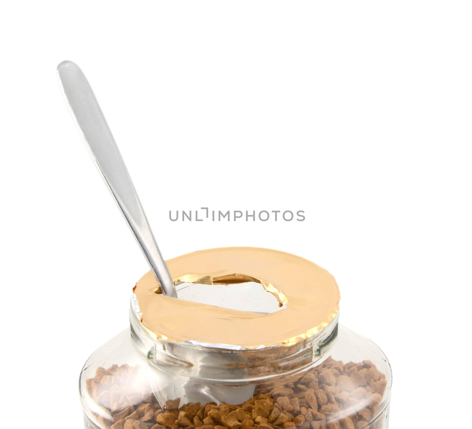 Metal teaspoon rests in a freshly opened jar of aromatic instant coffee granules - with copy space, isolated on a white background