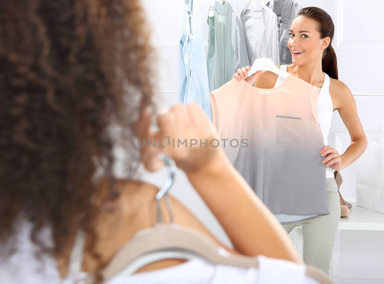 Two women shopping in boutique clothing, mulatto and Caucasian