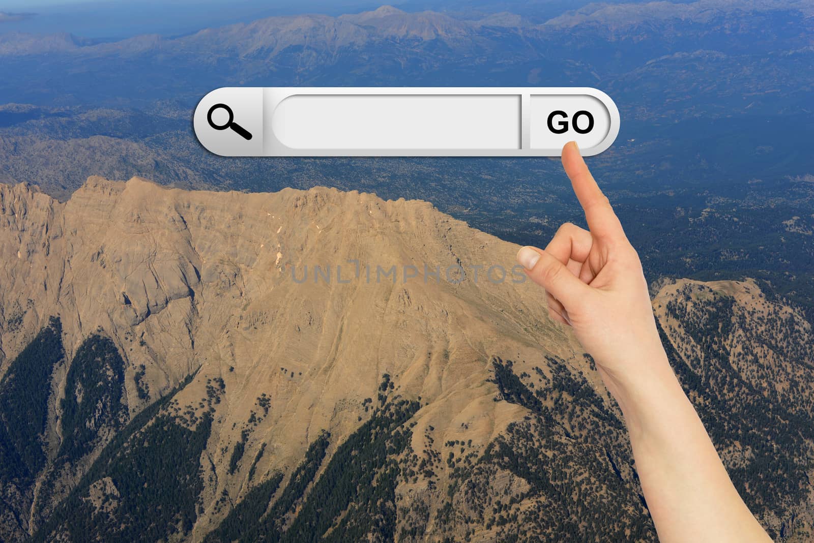 Human hand indicates the search bar in browser. Mountain and sky on background