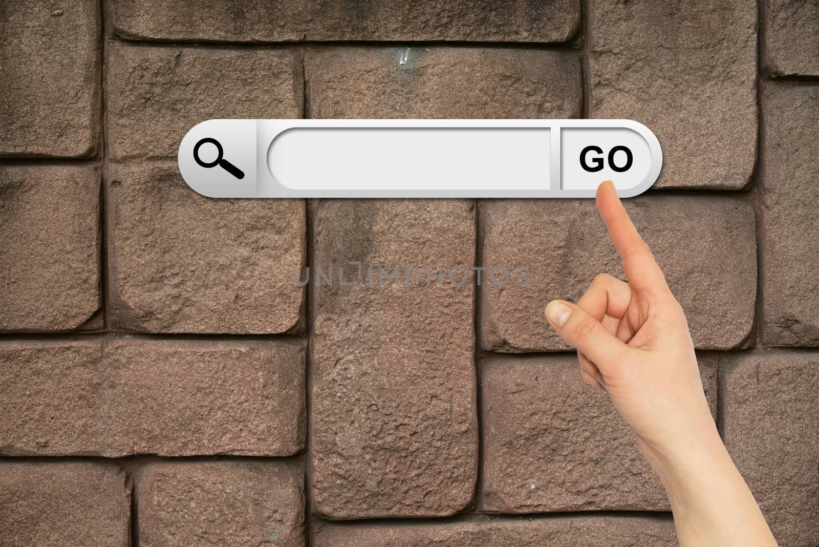 Human hand indicates the search bar in browser. Wall of brown bricks on background