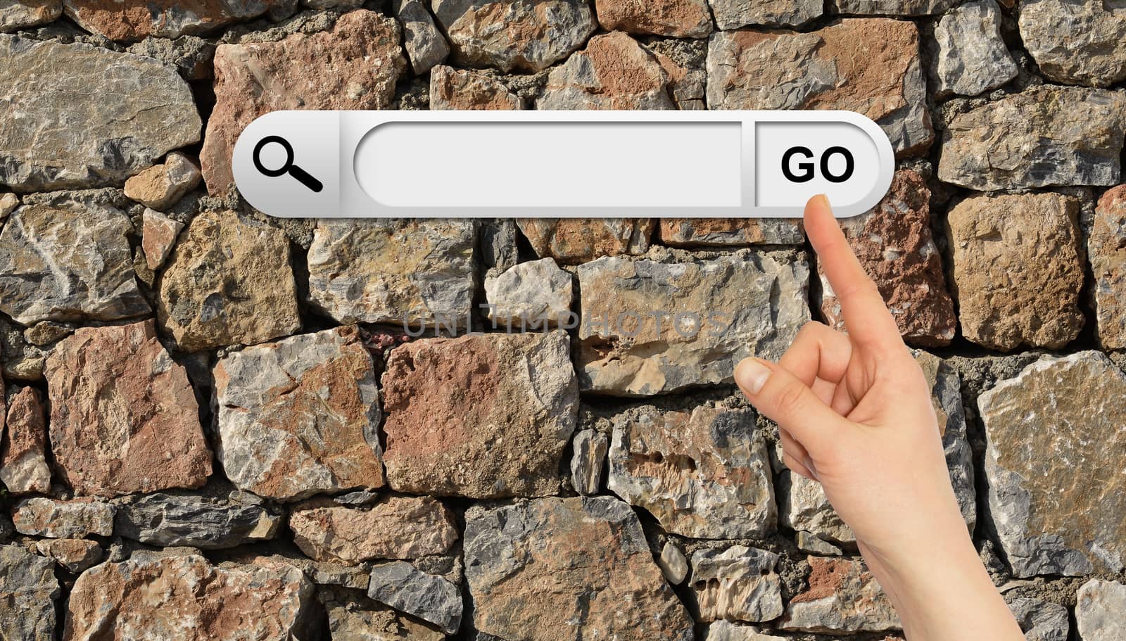 Human hand indicates the search bar in browser. Wall of natural bricks on background