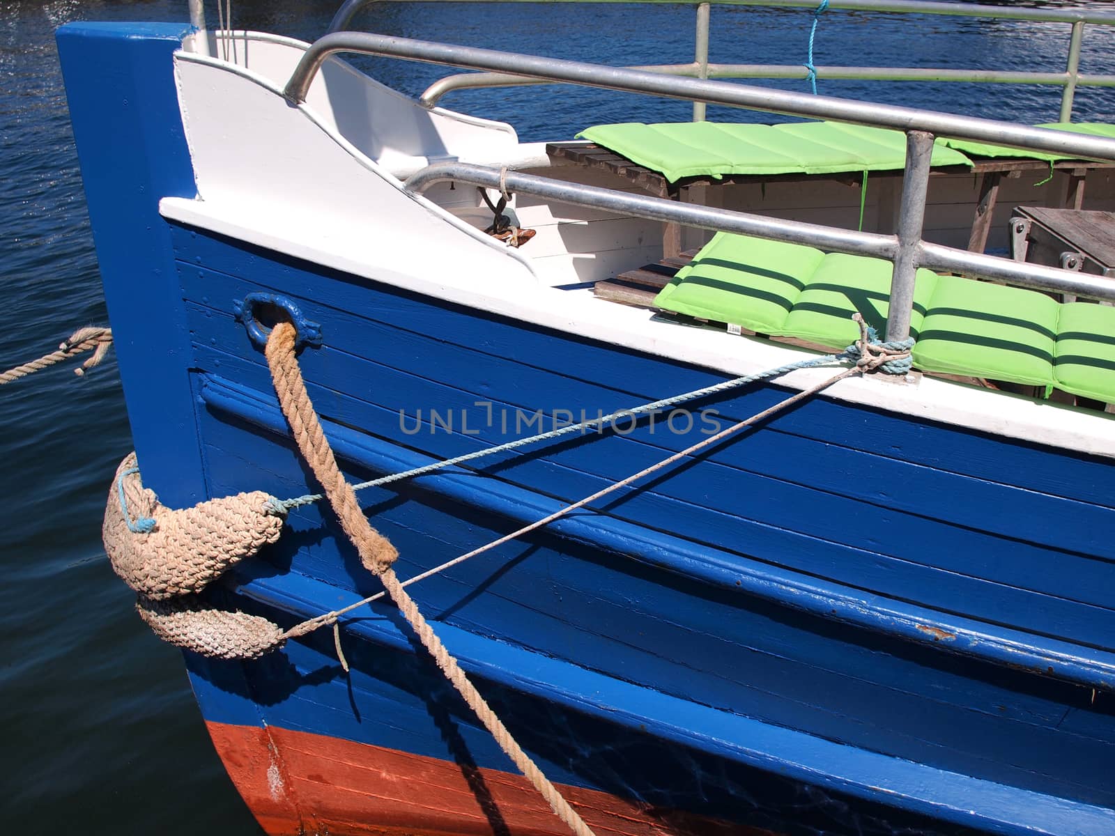 Prow of a small wooden tour boat docking in a marina 