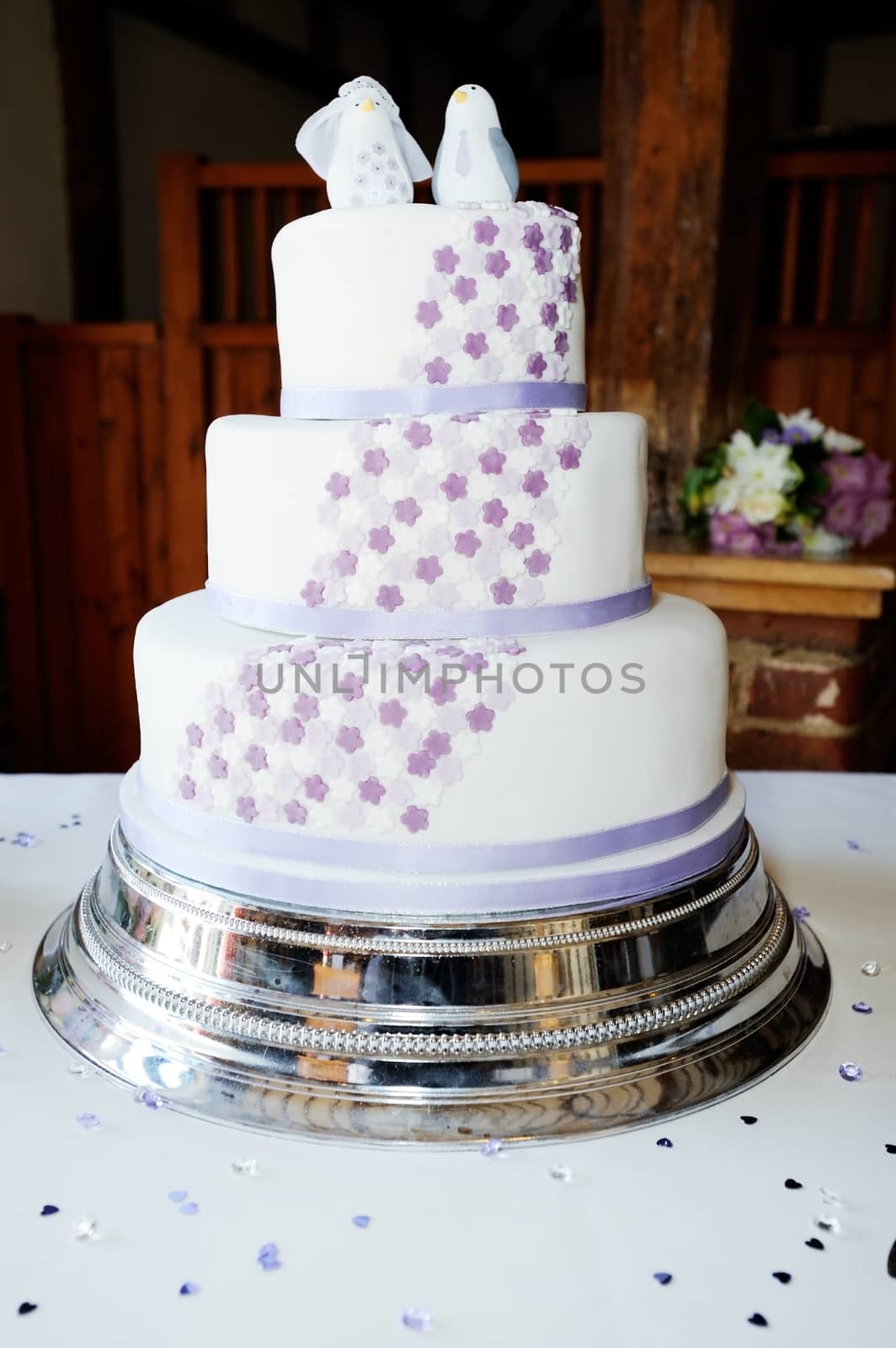 Wedding cake at reception decorated with lilac flowers