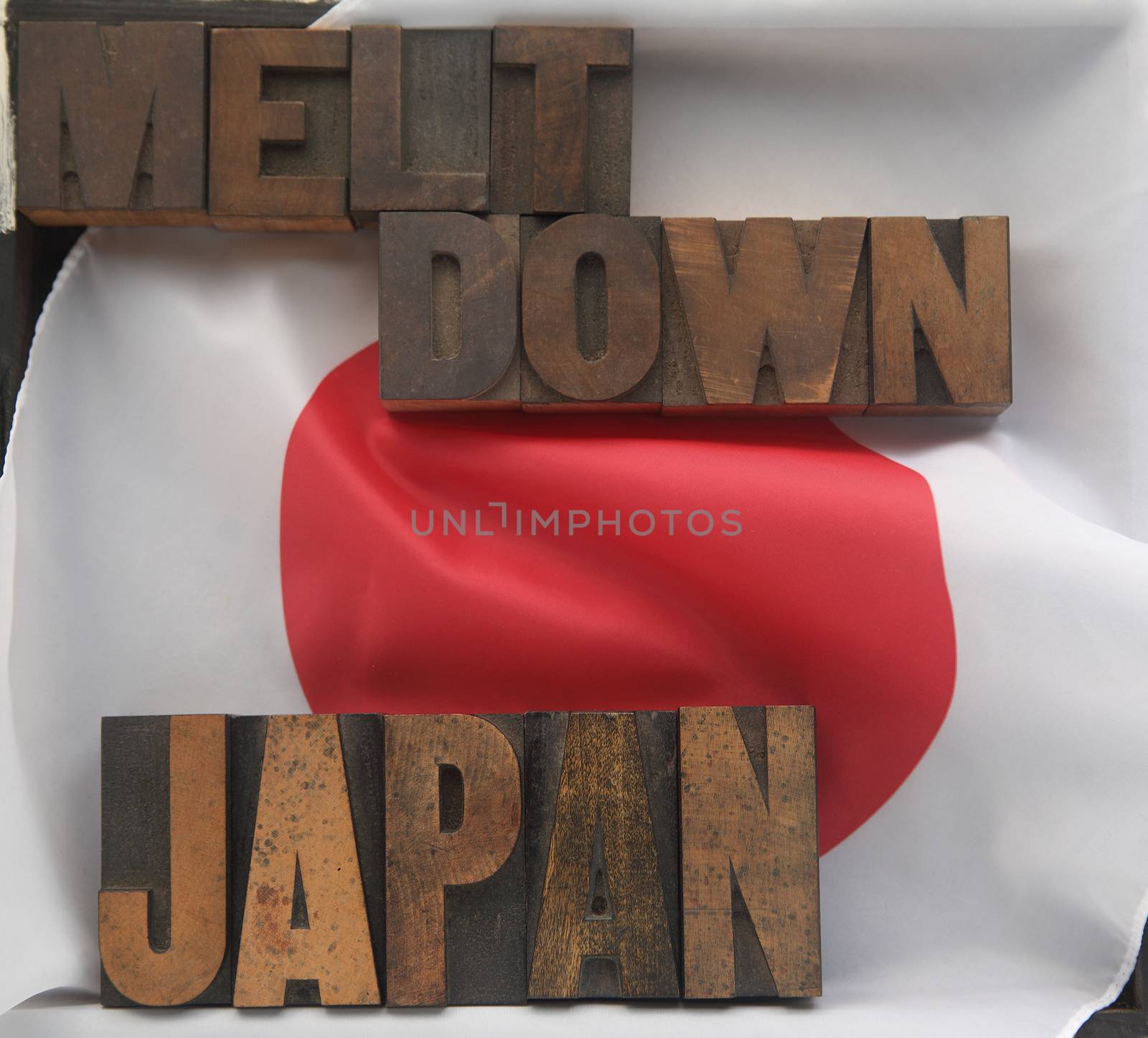 the words Japan and meltdown in old wood type on a Japanese flag