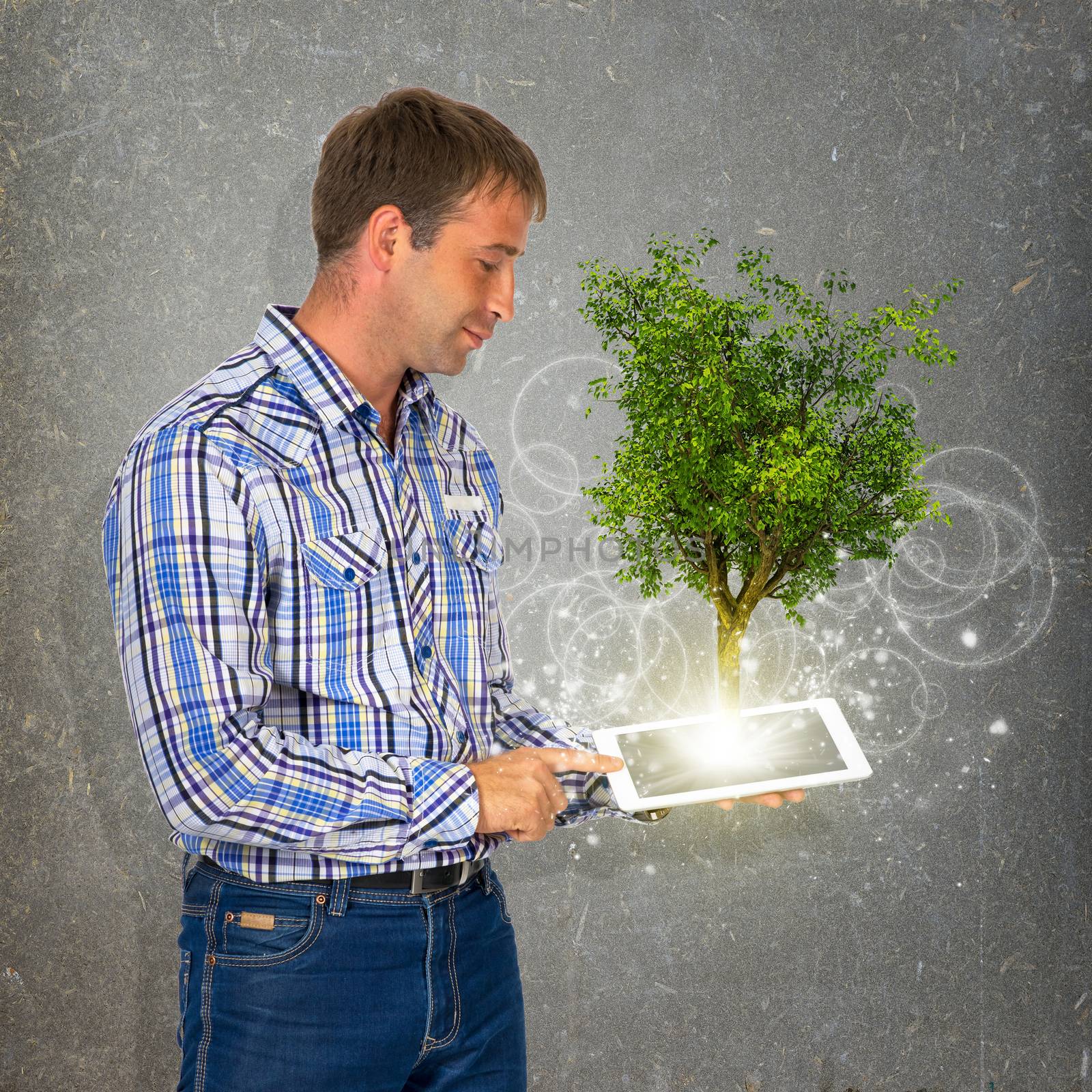 Man hold tablet pc with green tree by cherezoff