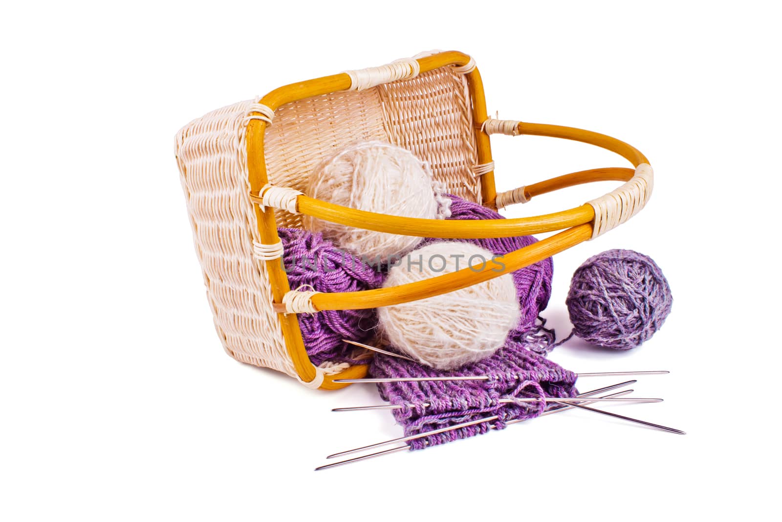 Basket with balls of wool yarn and knitting needles isolated on a white background