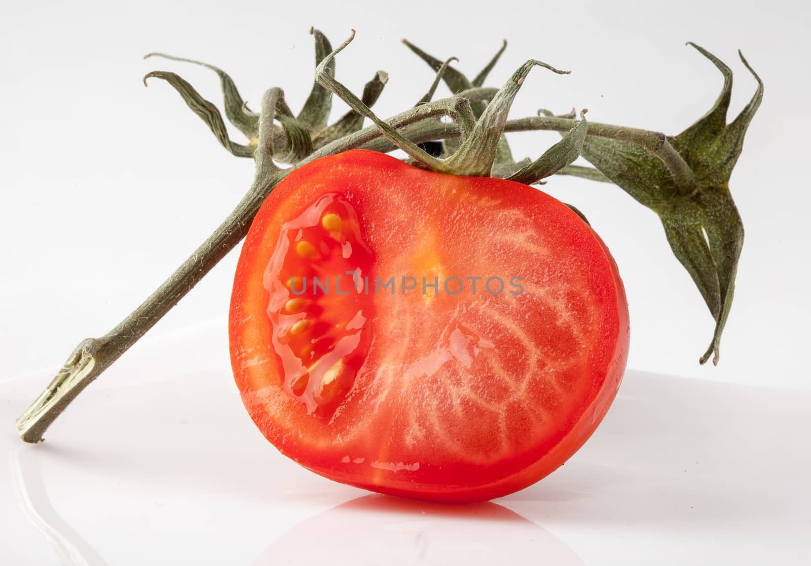 Red half of tomato with green branch