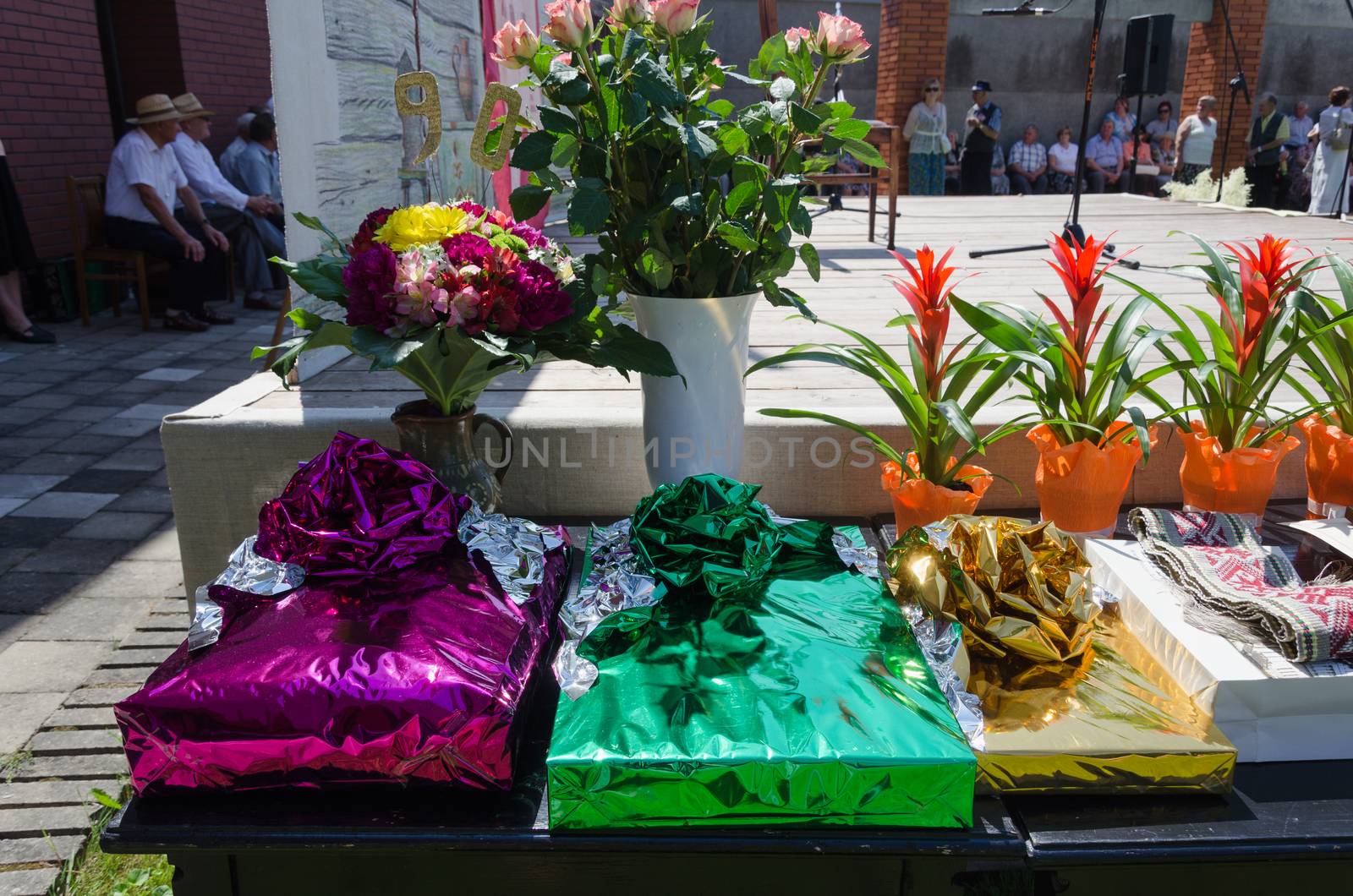 gift in glossy paper and flower roses bouquets and pots on the table city festival event outdoor