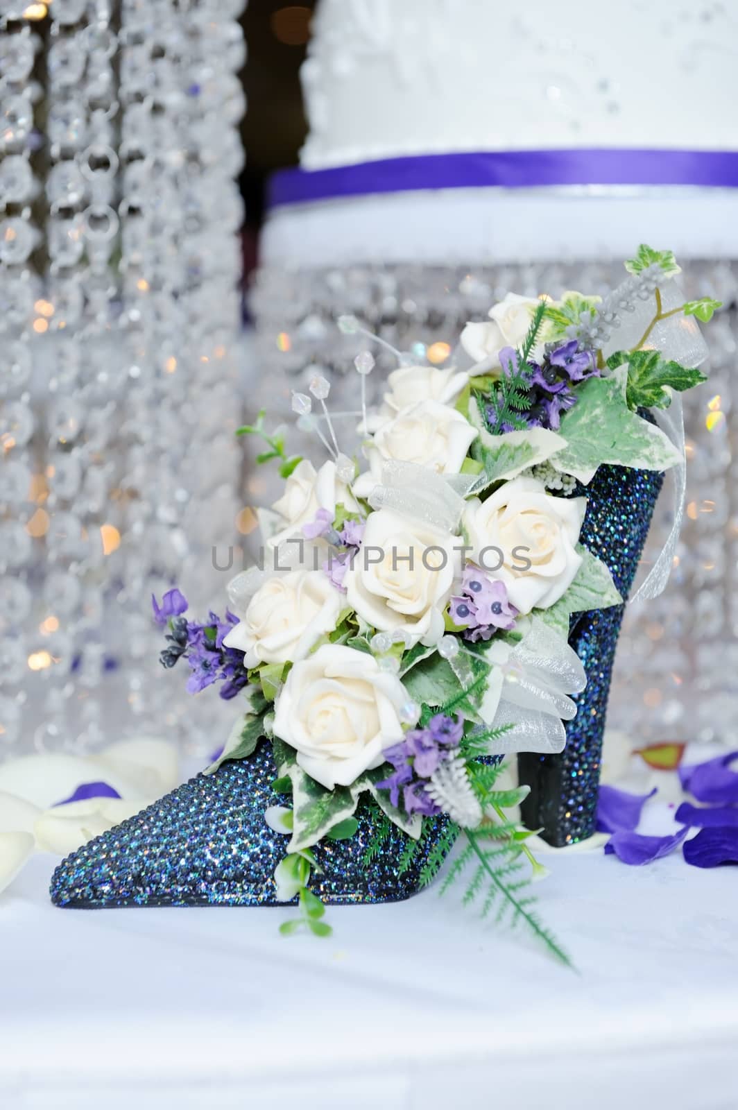 White rose in blue shoe decorate wedding reception with cake in background