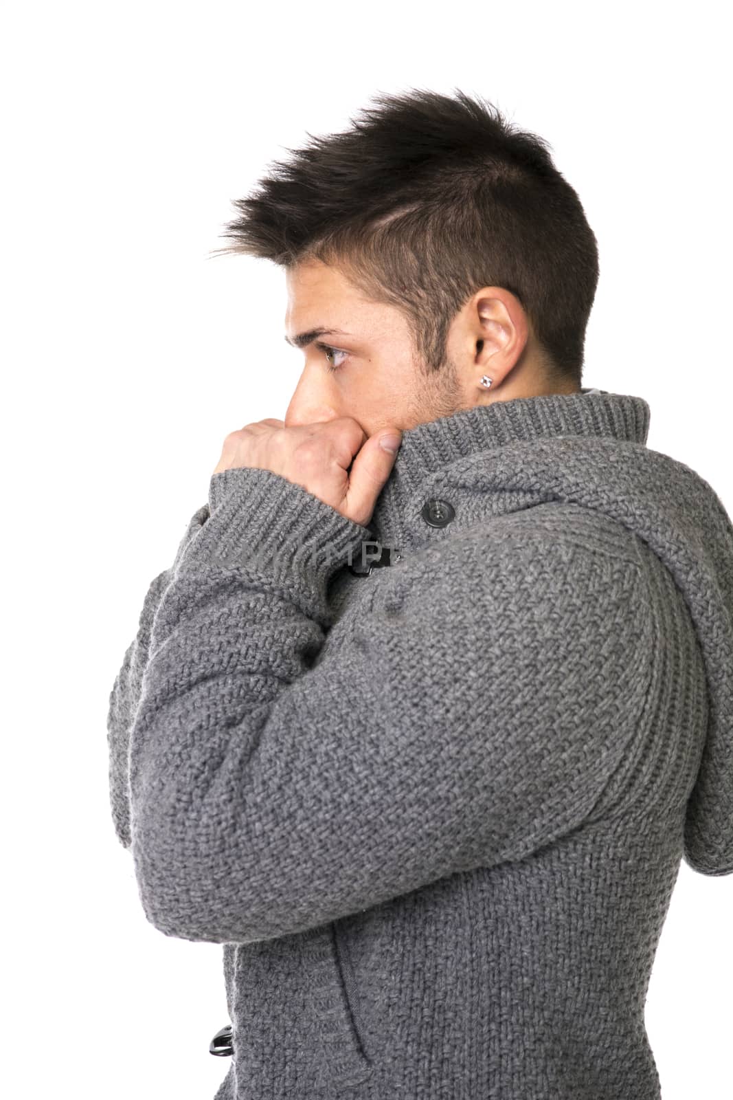 Profile of young man wearing winter hoodie sweater covering mouth with hands.