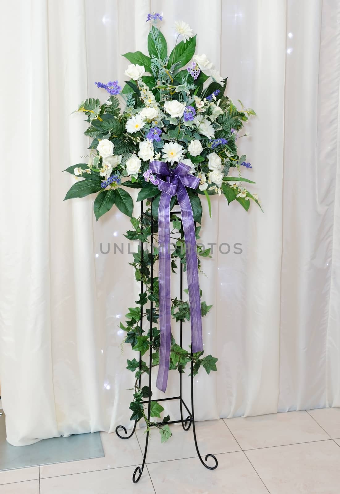 White and purple flower arrangement on stand at wedding reception