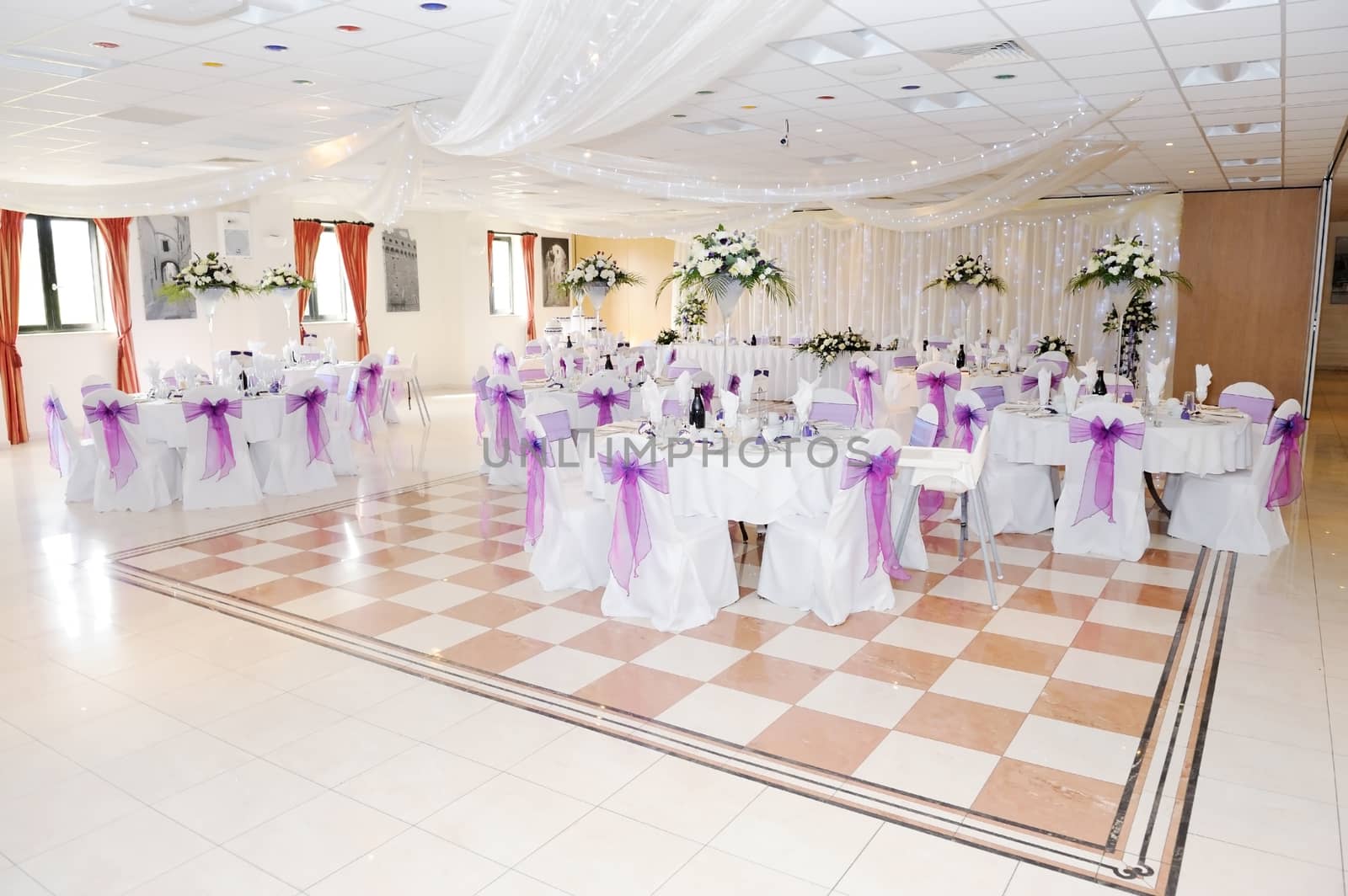 Wedding reception setting decorated with purple ribbon and white flowers