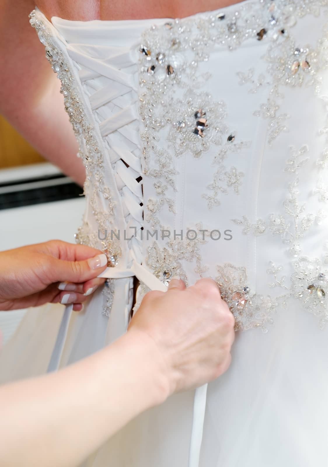 Brides dress being fastened up on wedding day