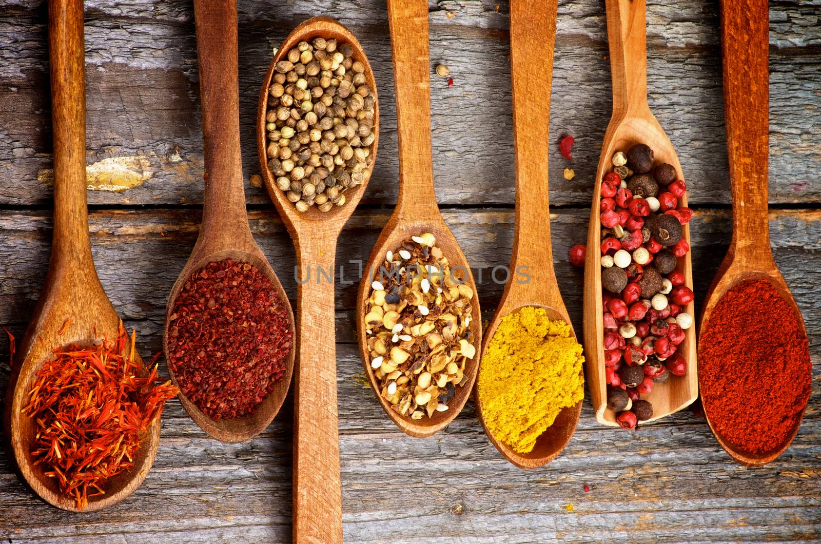 Wooden Spoons with Saffron, Sumac, Coriander, Dried Chili, Curry Powder, Mixed Pepper and Paprika on Rustic Wooden background. Top View