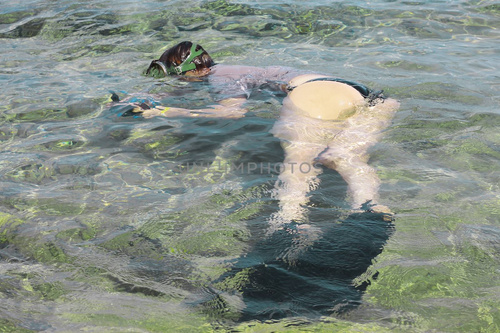 Woman photographer diving into water of Red sea