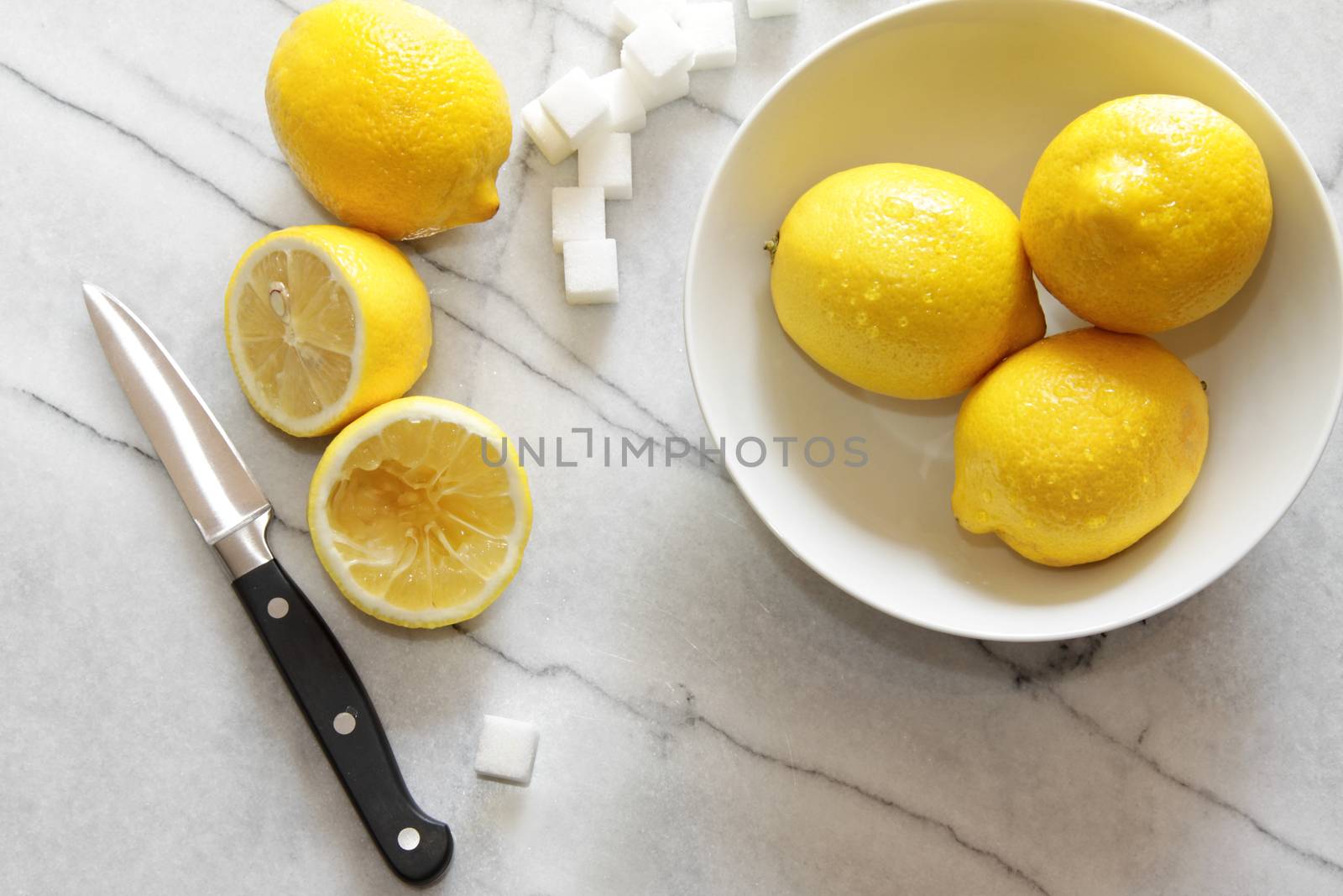 Fresh lemons and sugar cubes on marble counter  by Sandralise