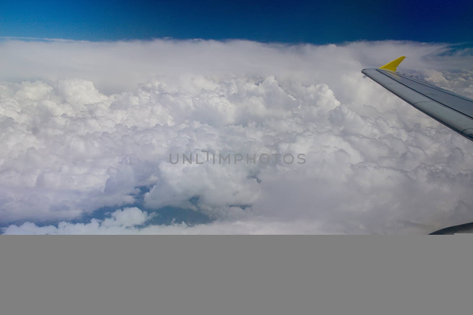 Photo shows details of white clouds, blue sky and plane.