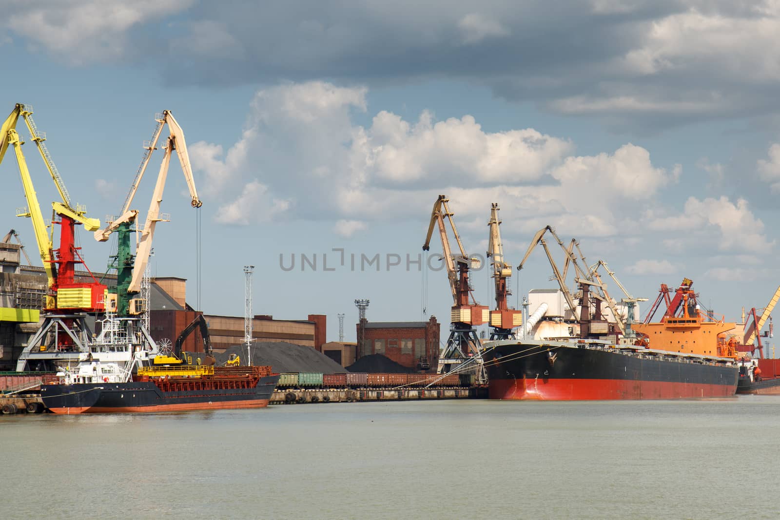 Industrial harbor with two freight ships with coal being loaded in
