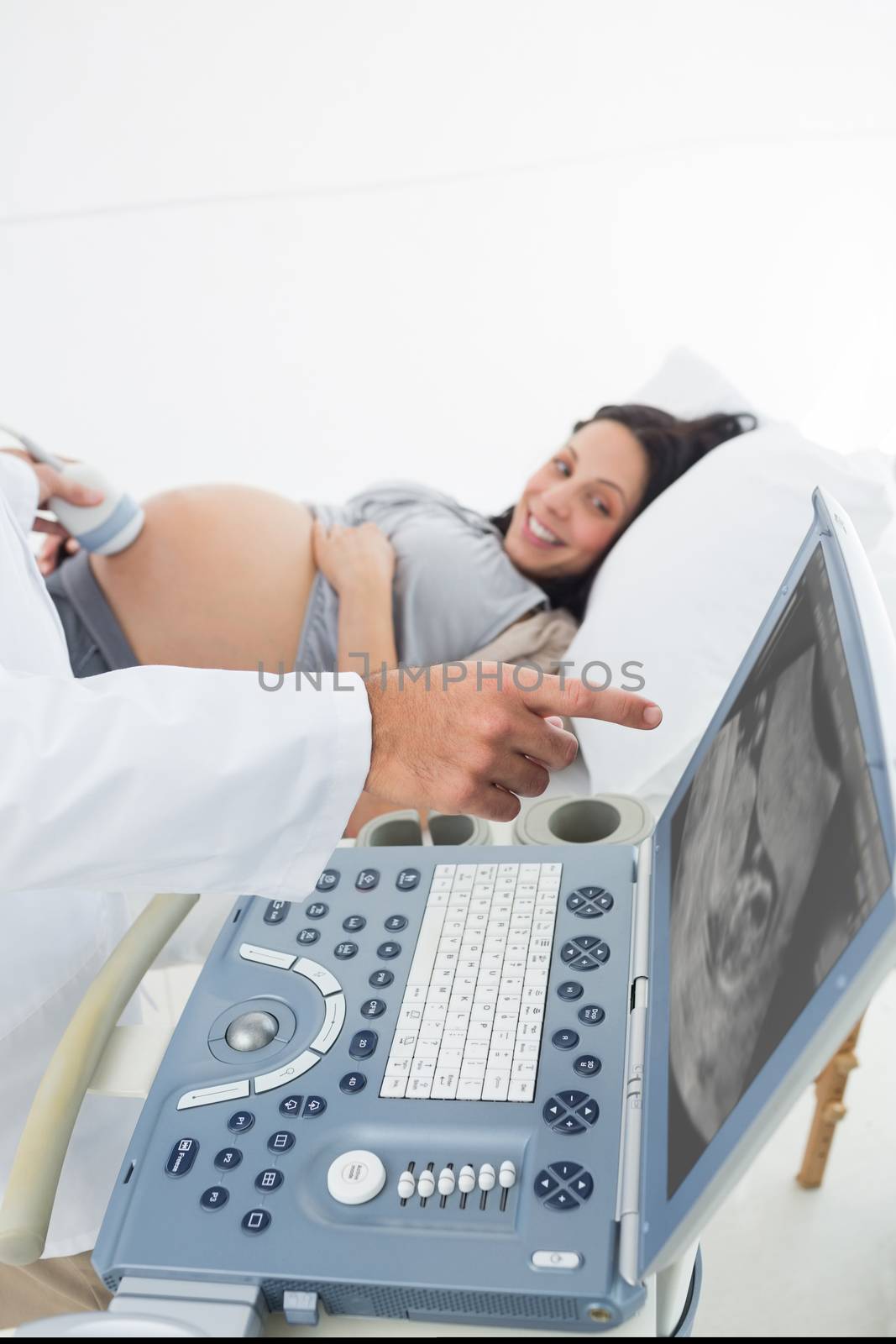 Cropped image of doctor showing ultrasound monitor to pregnant woman in hospital