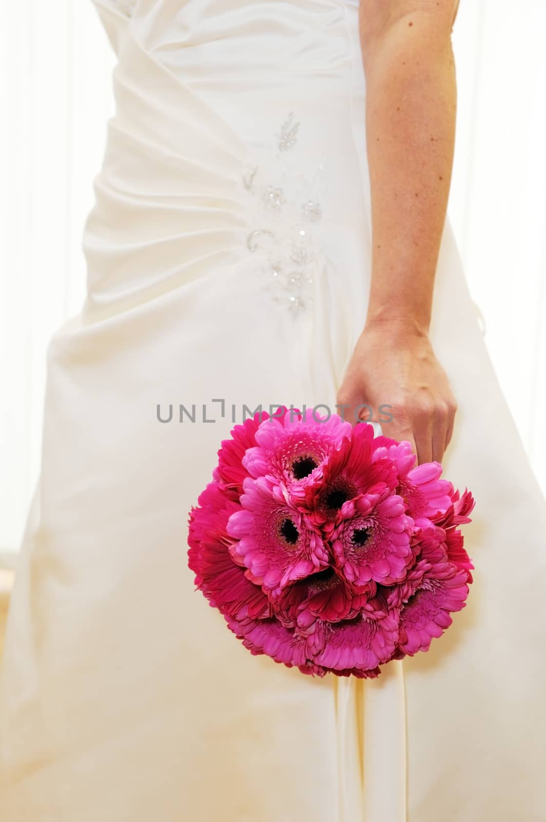 Bride holds pink bouet of flowers on wedding day