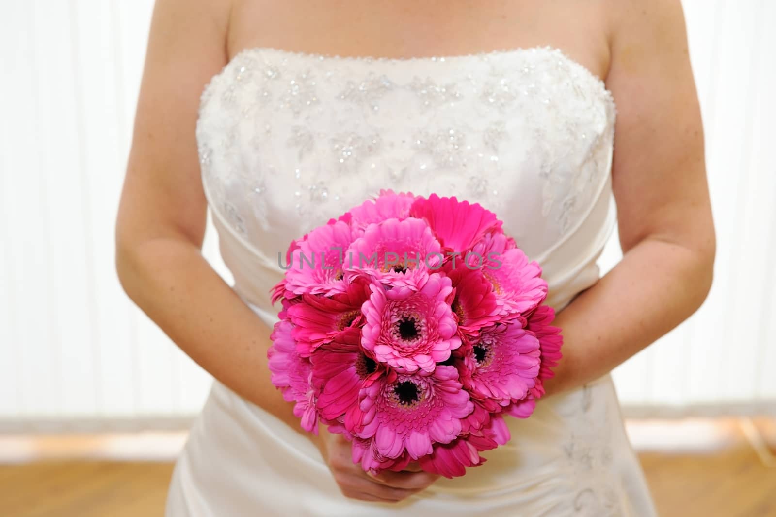 Bride holding bouquet of pink flowers before wedding