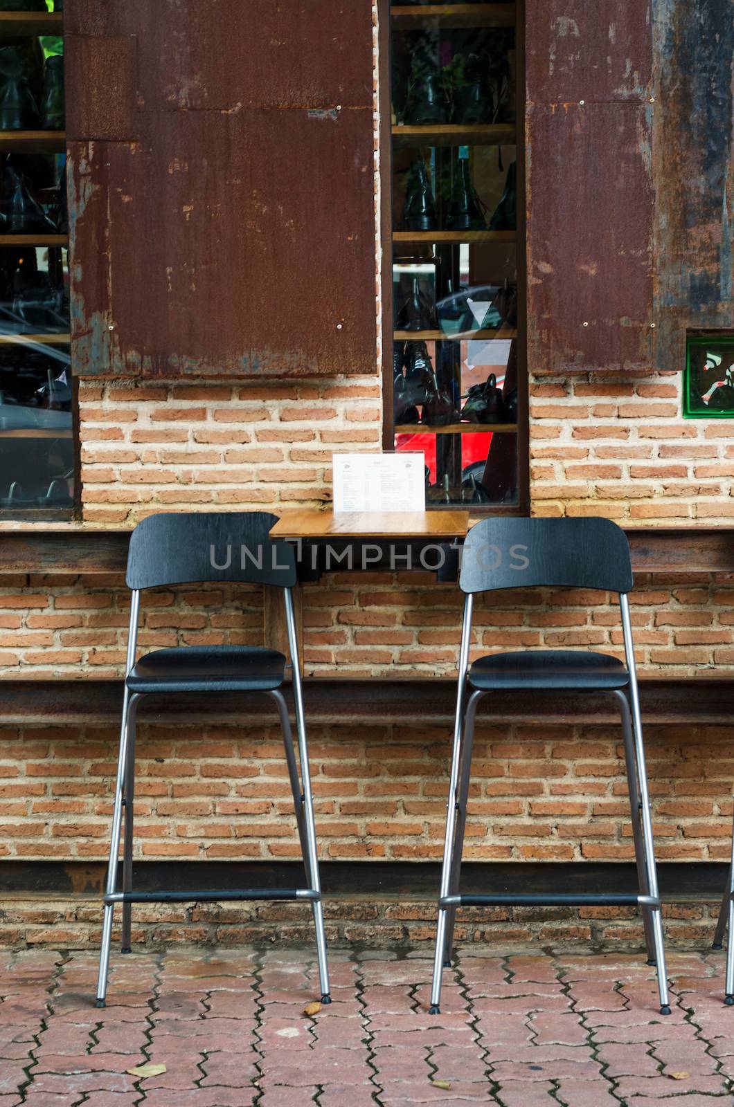 Two cafe chairs against brick wall by siraanamwong