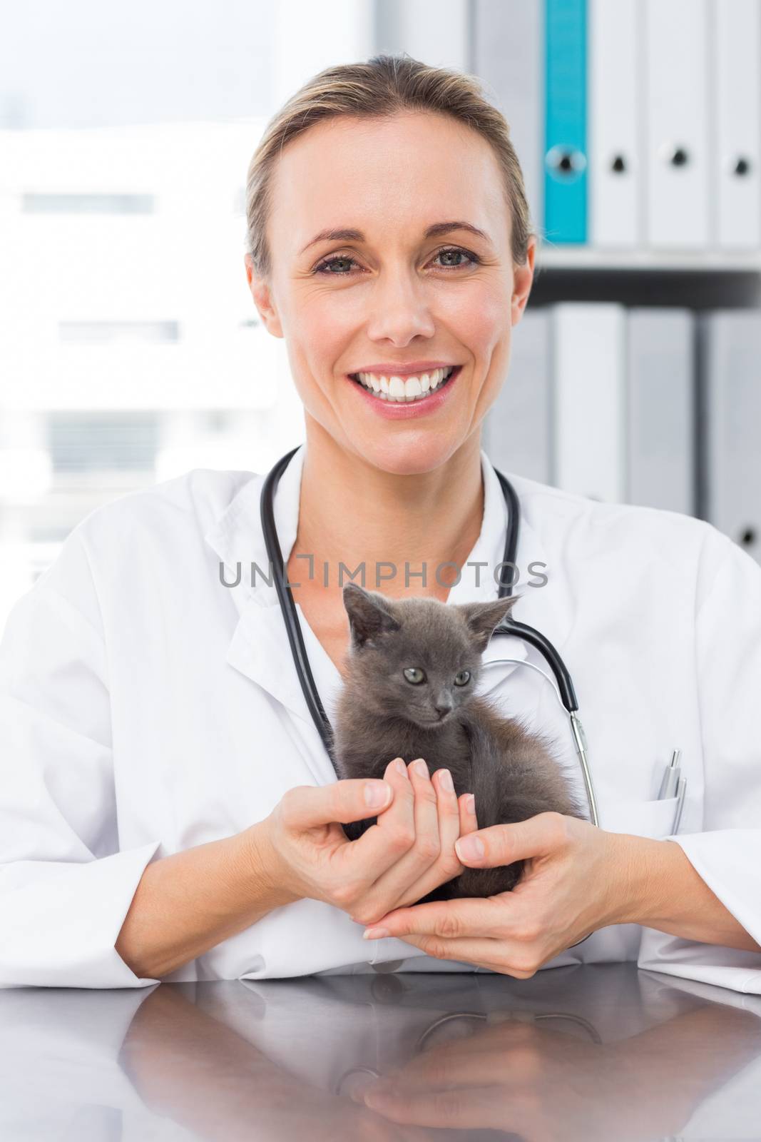 Portrait of happy female vet holding kitten in clinic