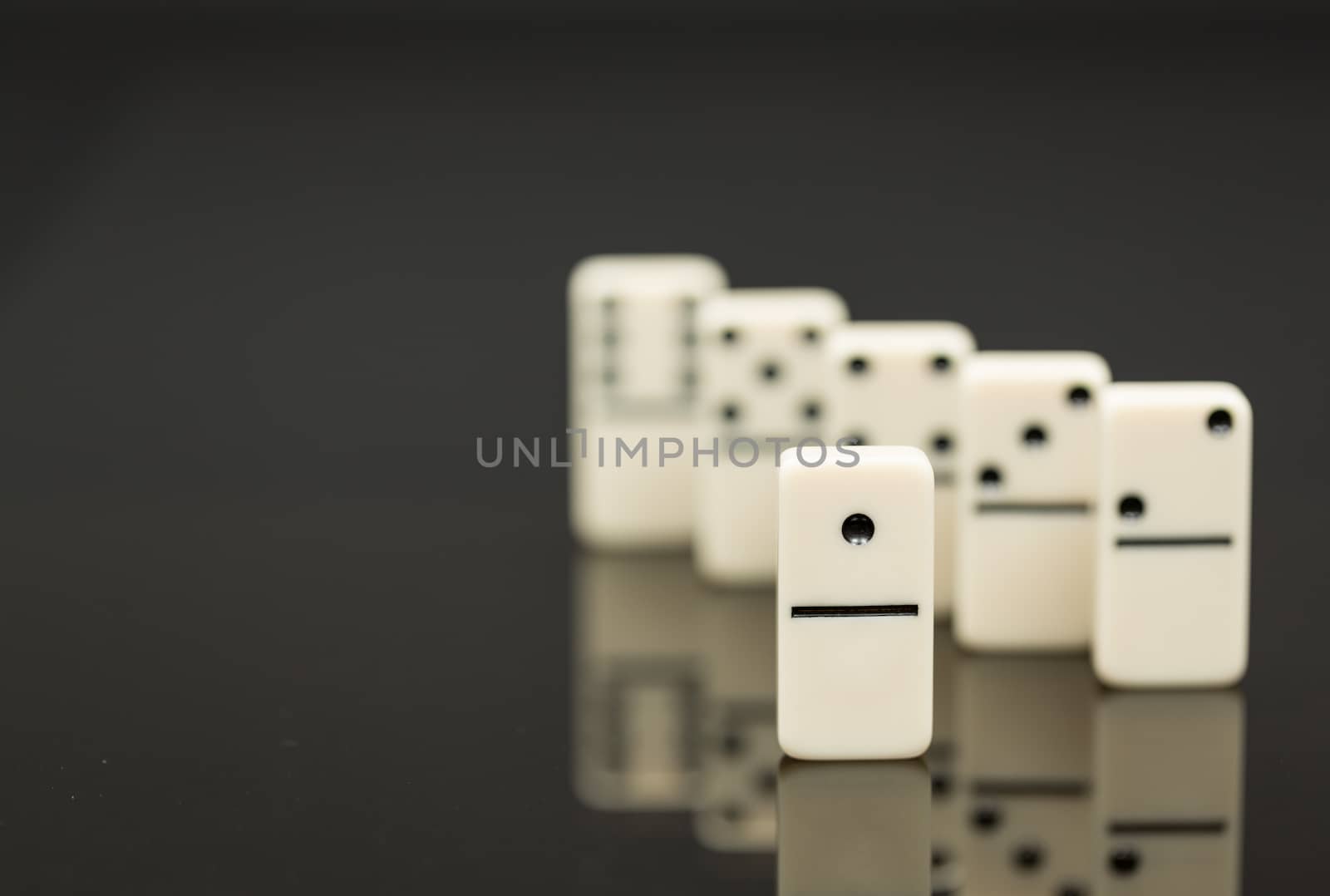 Number One domino in front of peers as concept image for success, innovation, leadership, winning and leader of the pack