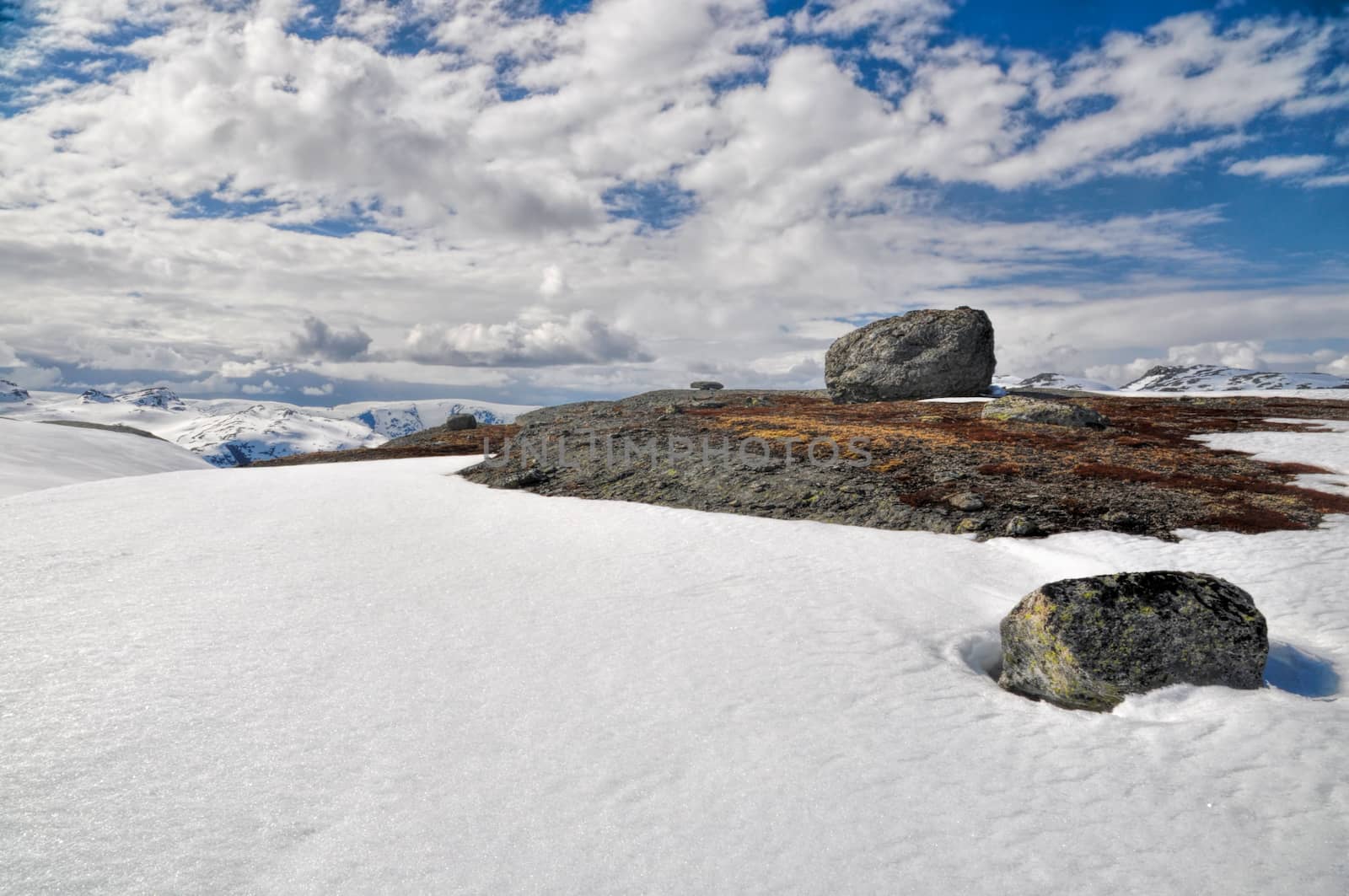 Big rock on a mossy mountain surrounded by snow, Norway