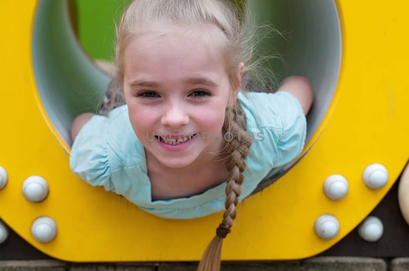 Adorable young girl sitting in crawl tube on the playground