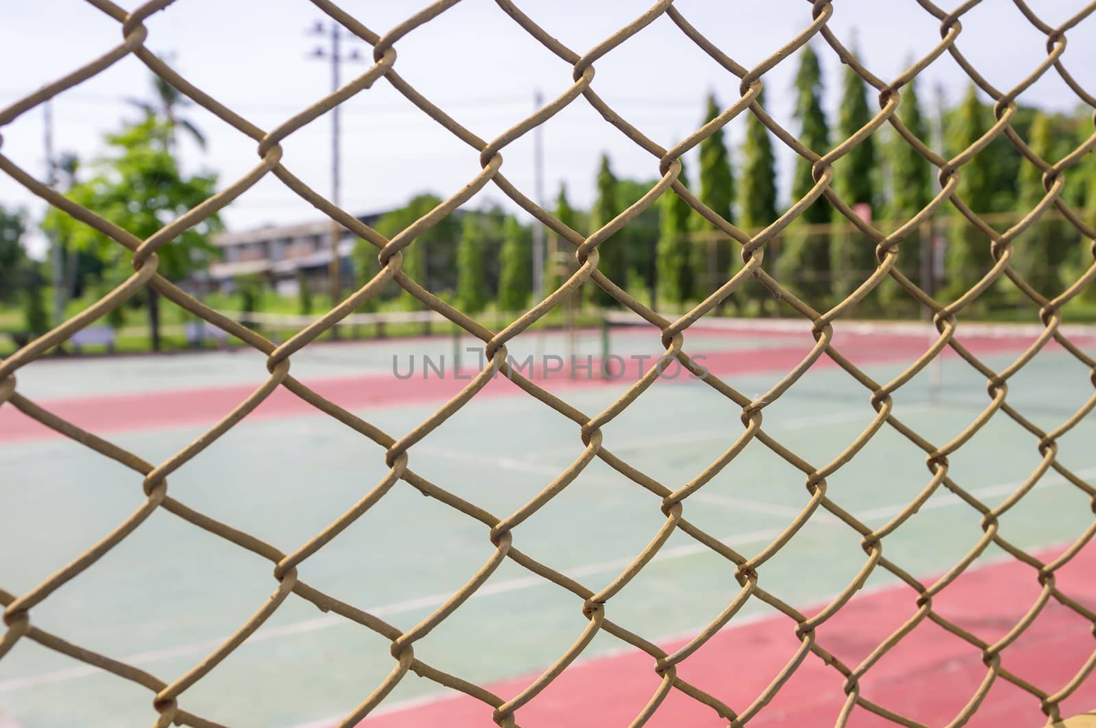 Metal mesh wire fence with blur tennis court background