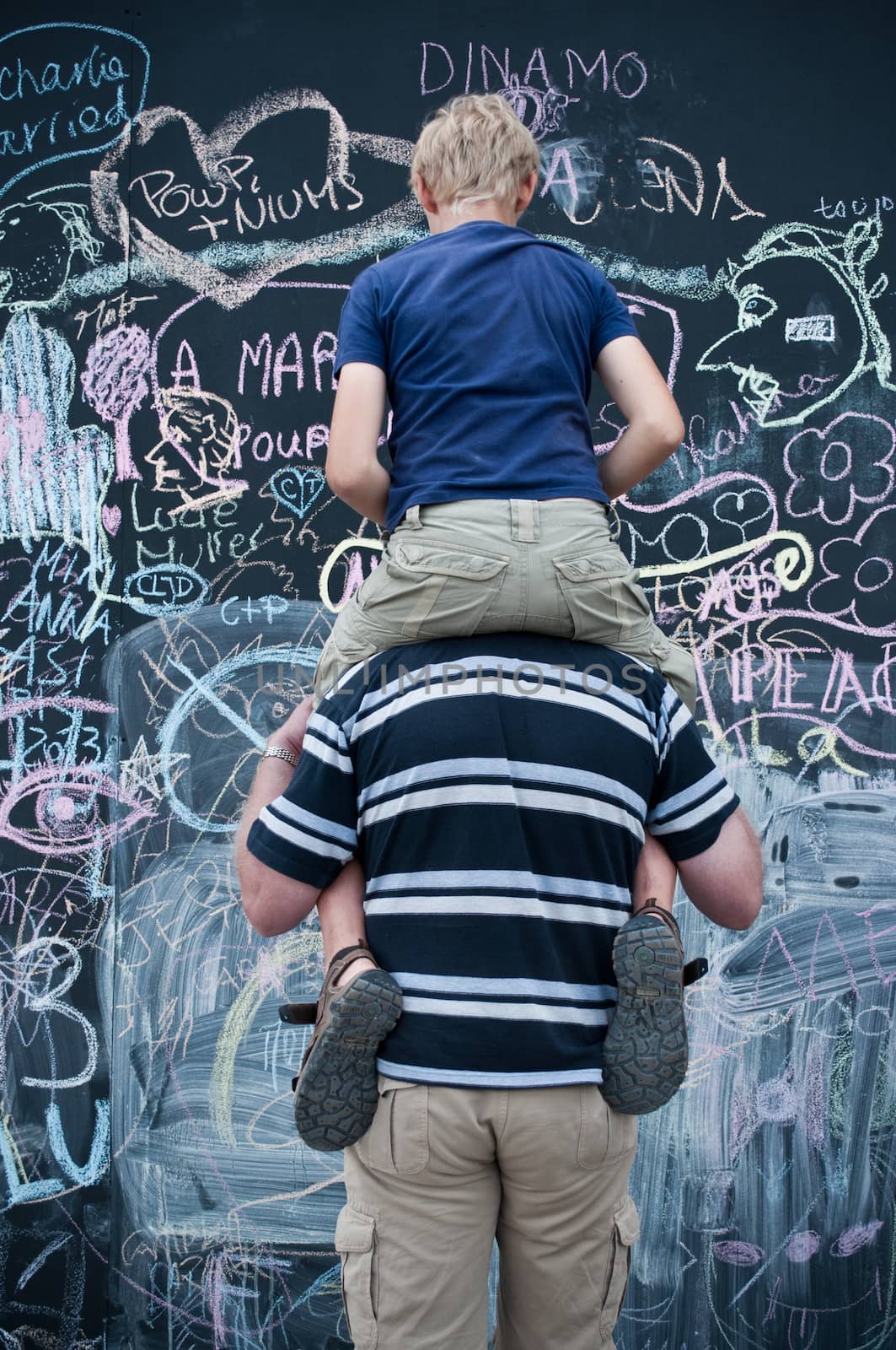 father and son  writing on big blackboard by NeydtStock