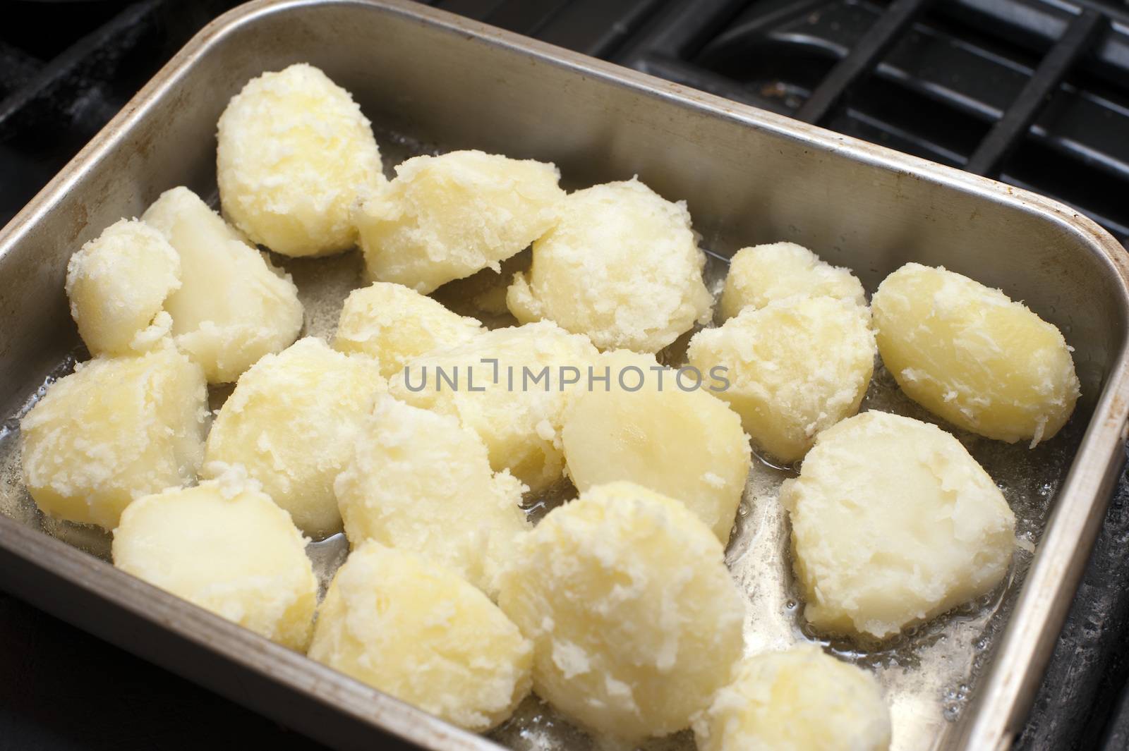 Preparing roast potatoes by par boiling them and placing them in an oven dish with oil to roast and crisp up