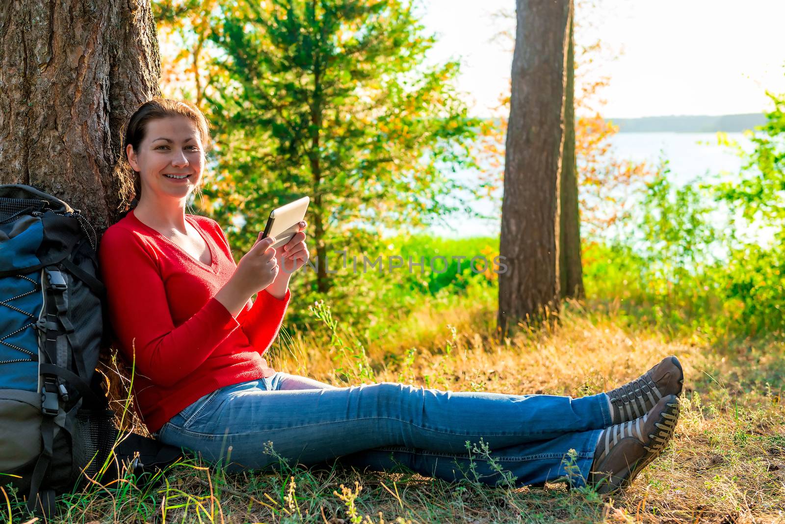 happy girl with the tablet resting in a campaign against a tree